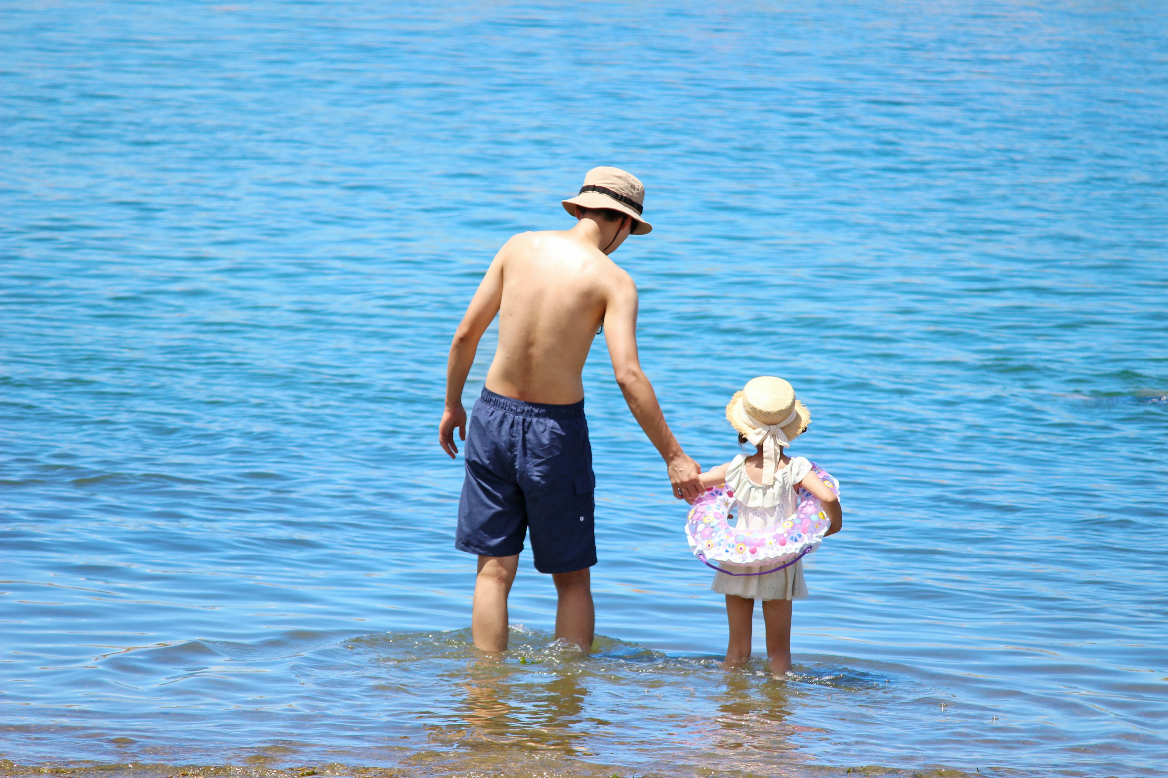 Un padre e una figlia che si bagnano nell'acqua bassa dell'oceano