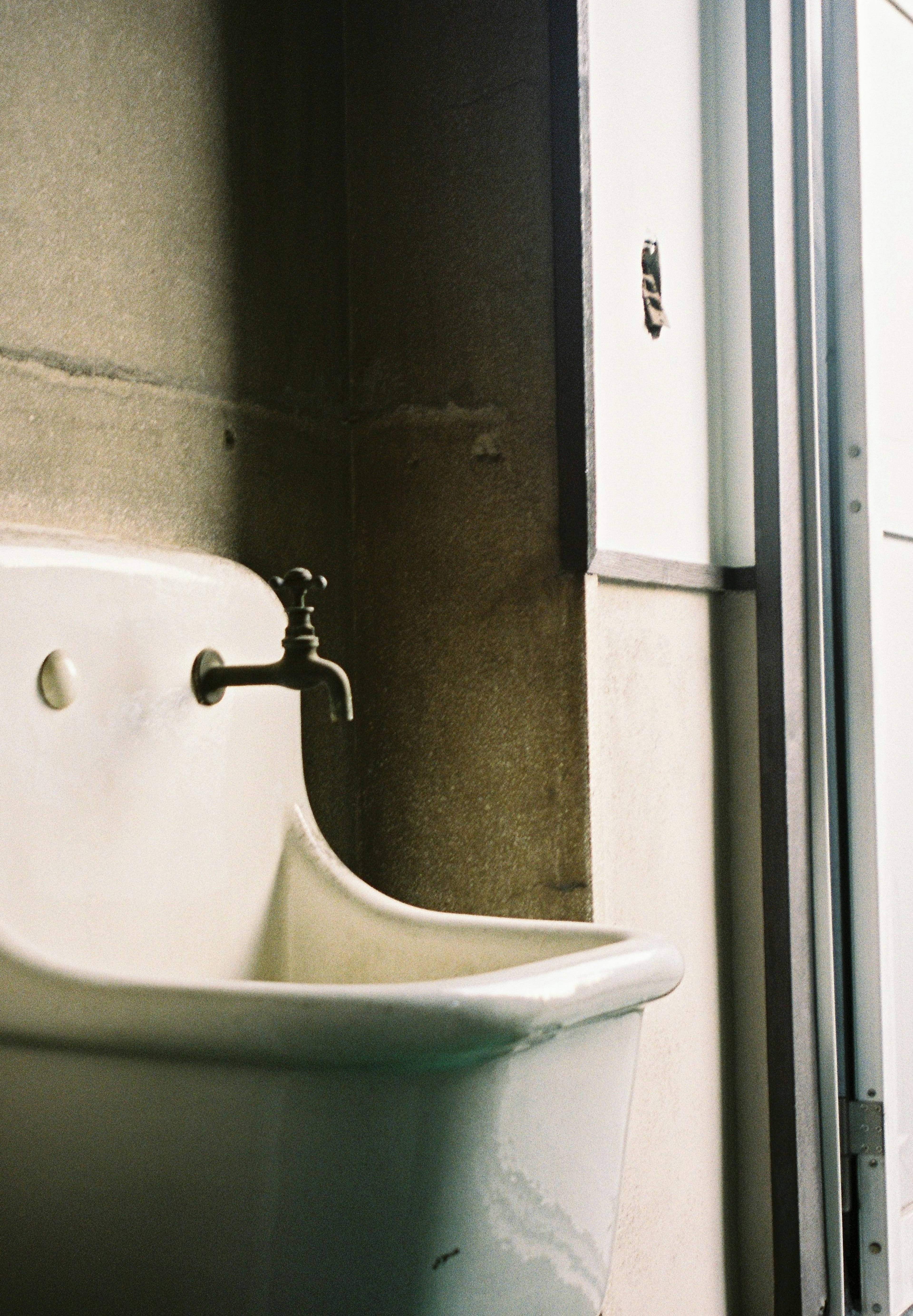 Imagen que muestra un lavabo blanco contra una pared de concreto