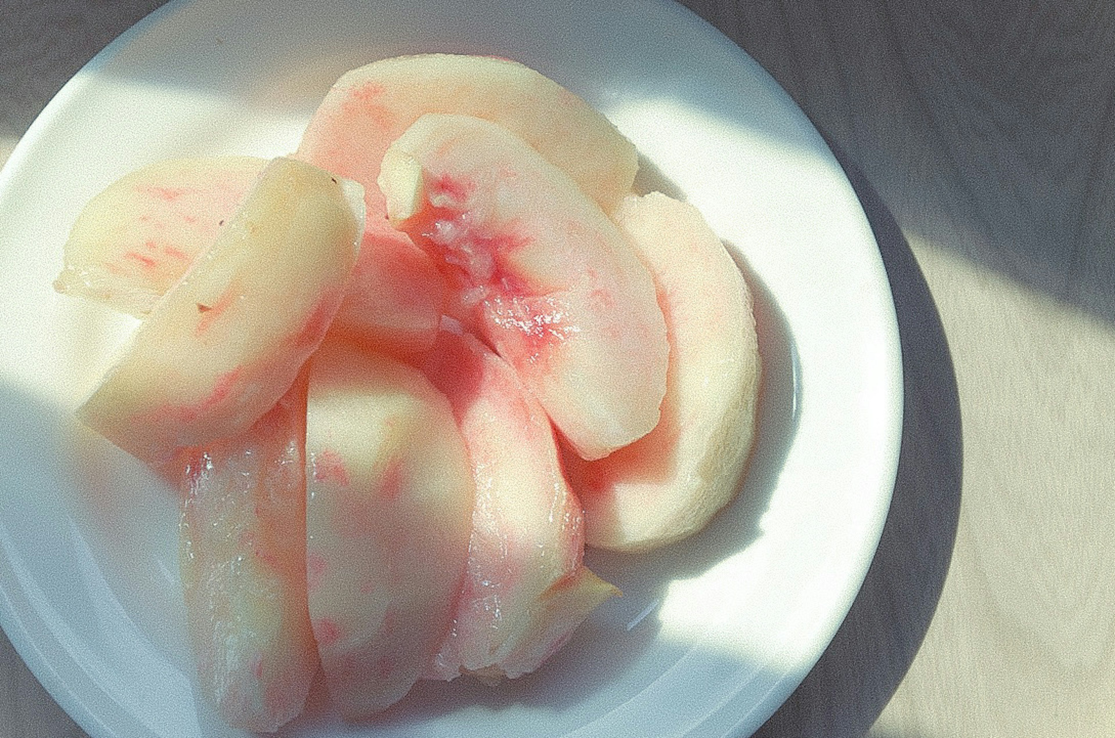 Slices of light pink peach on a white plate