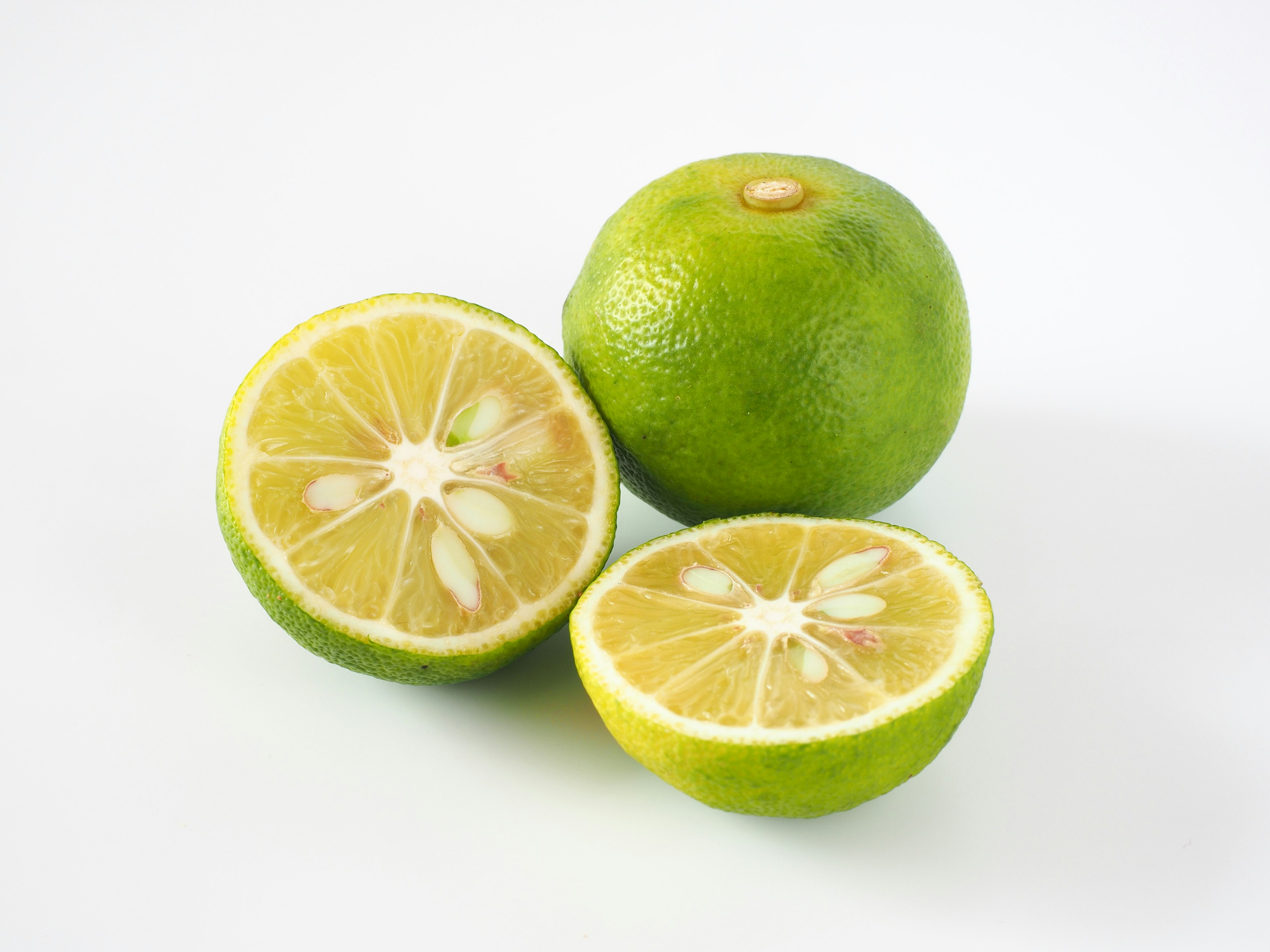 Green lemon with sliced half showcasing juicy segments