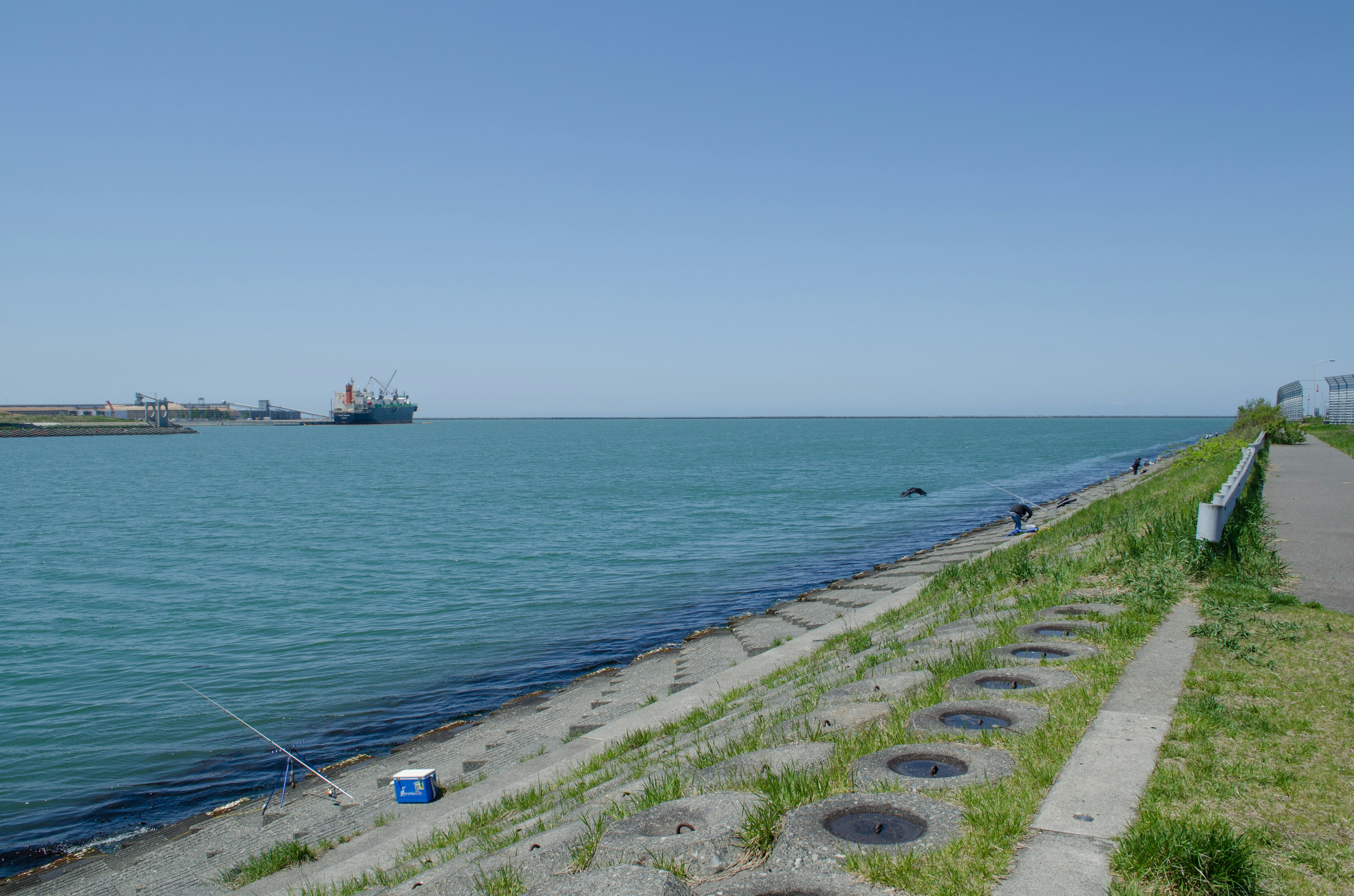 Scenic view of blue sea and clear sky with a person fishing