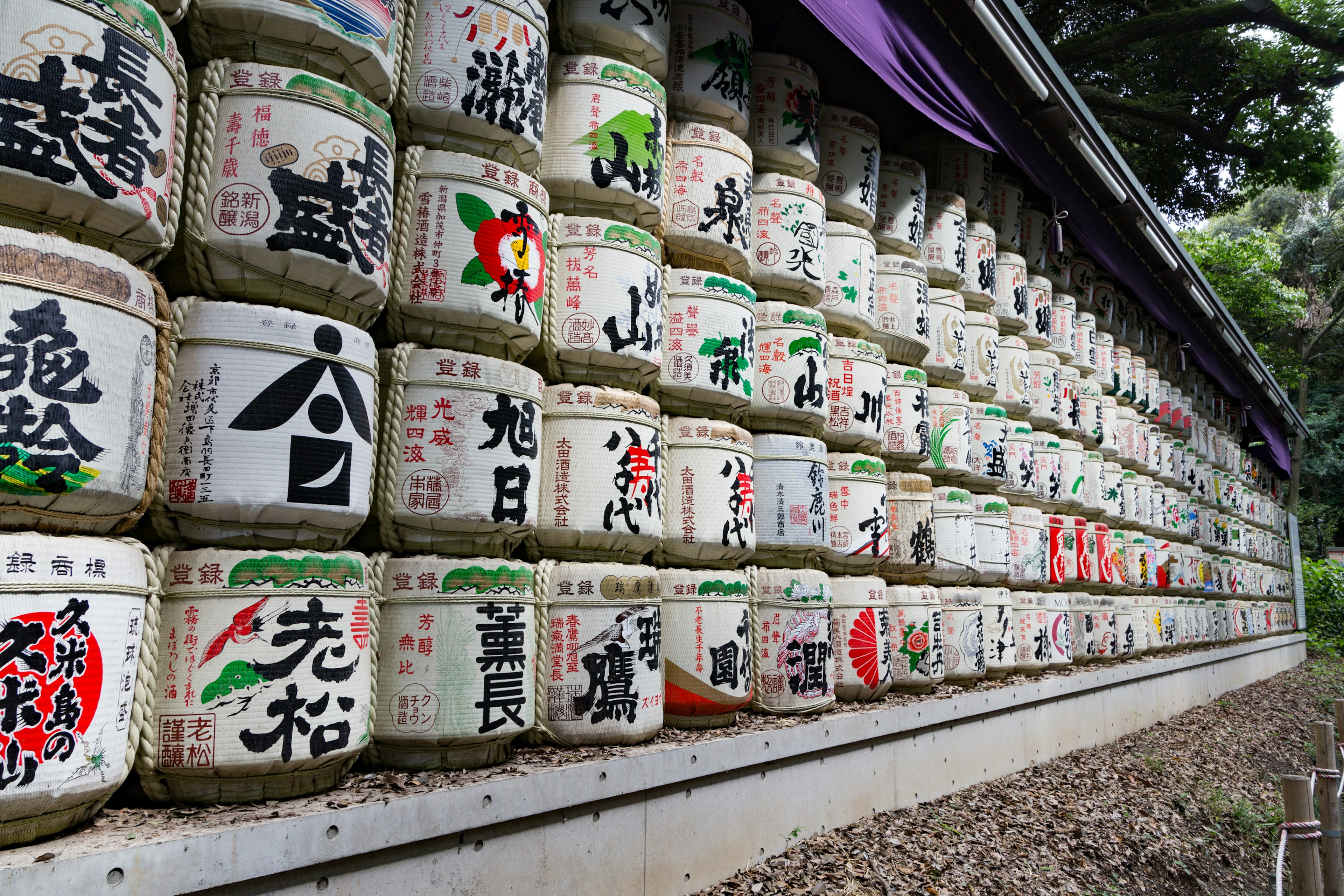 Mur de fûts de saké devant un sanctuaire avec des étiquettes colorées et des symboles de la culture japonaise