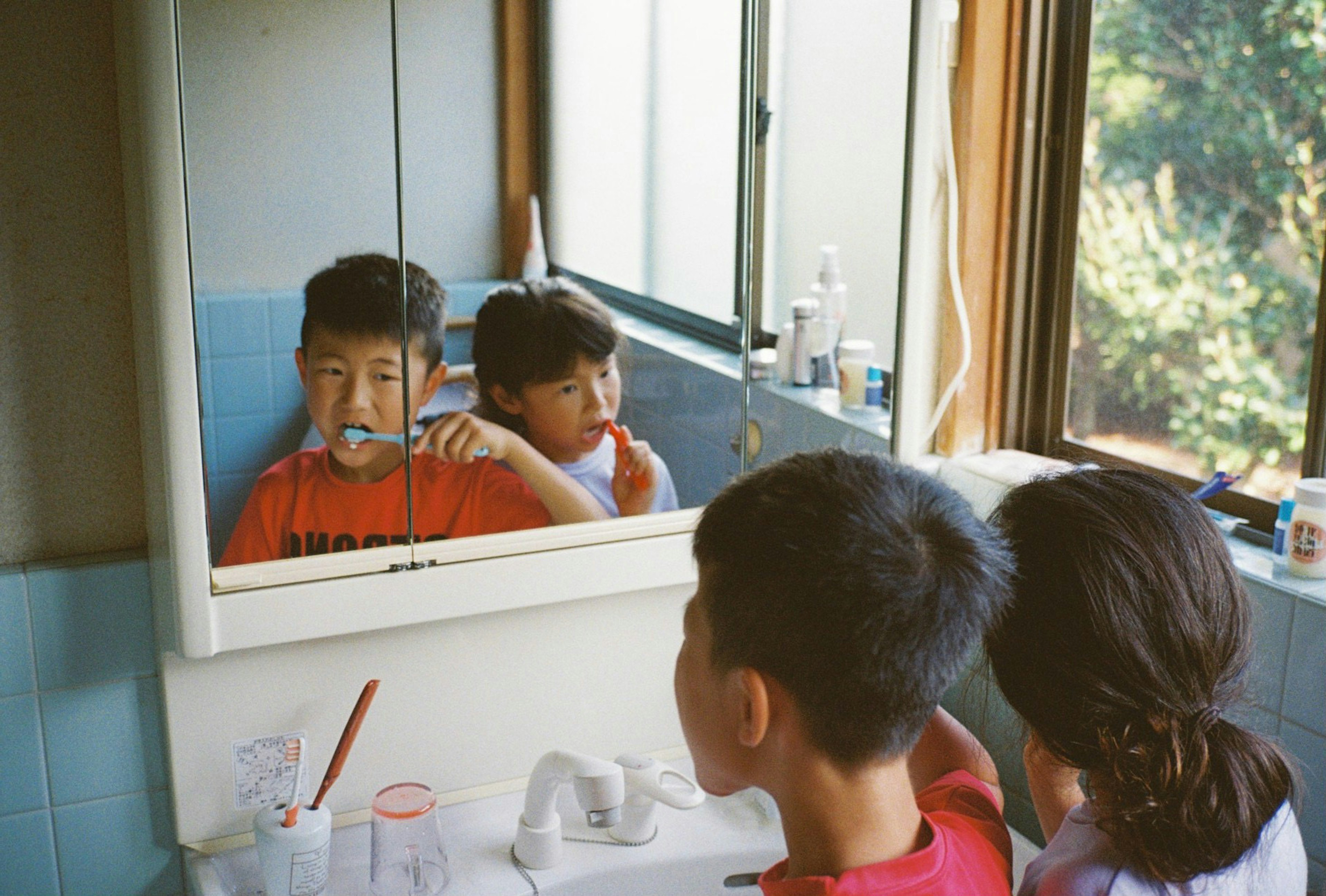 子供たちが鏡の前で歯を磨いている様子 窓からの自然光が差し込む明るいバスルーム
