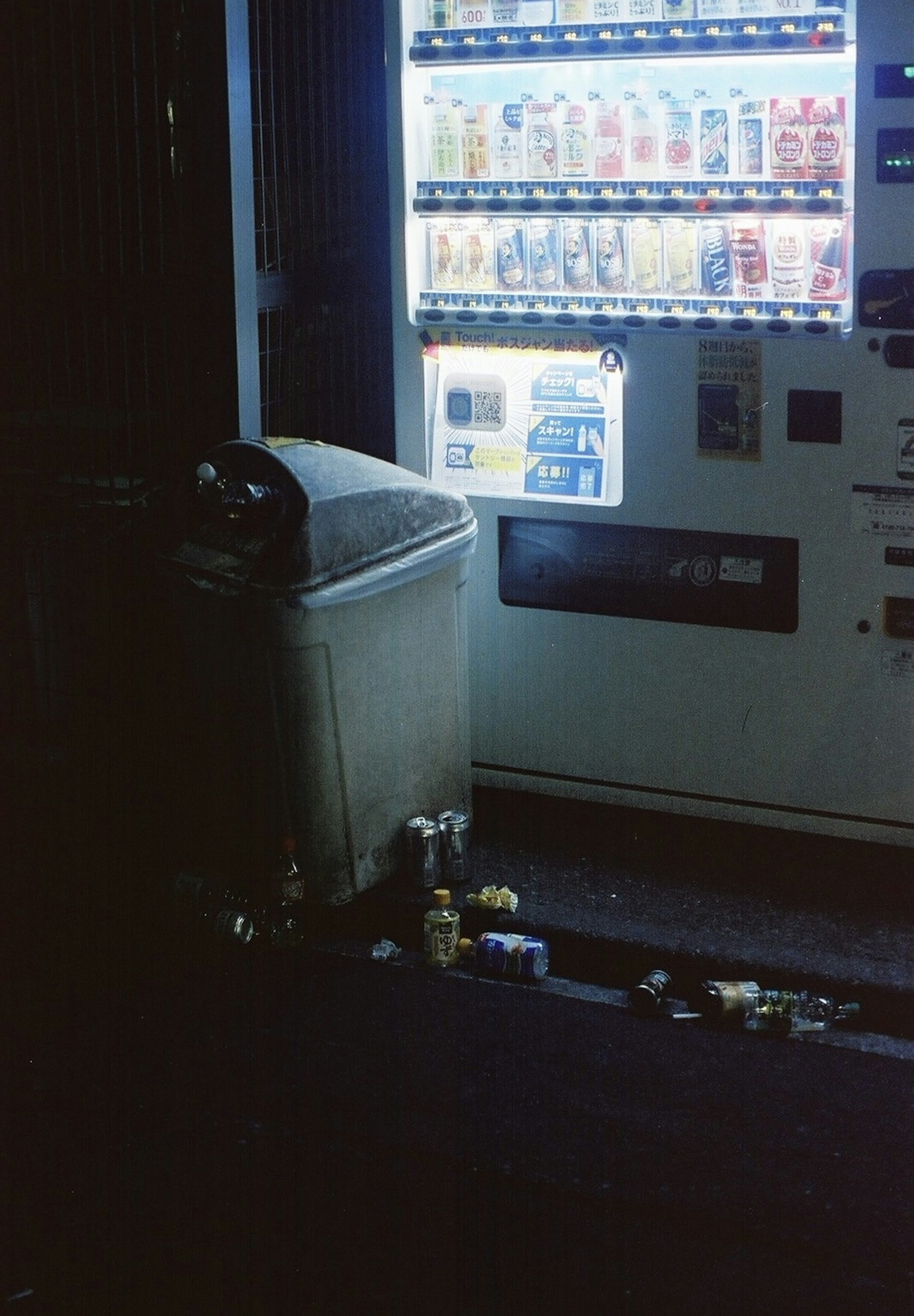 自動販売機とゴミ箱のある暗い通りの風景