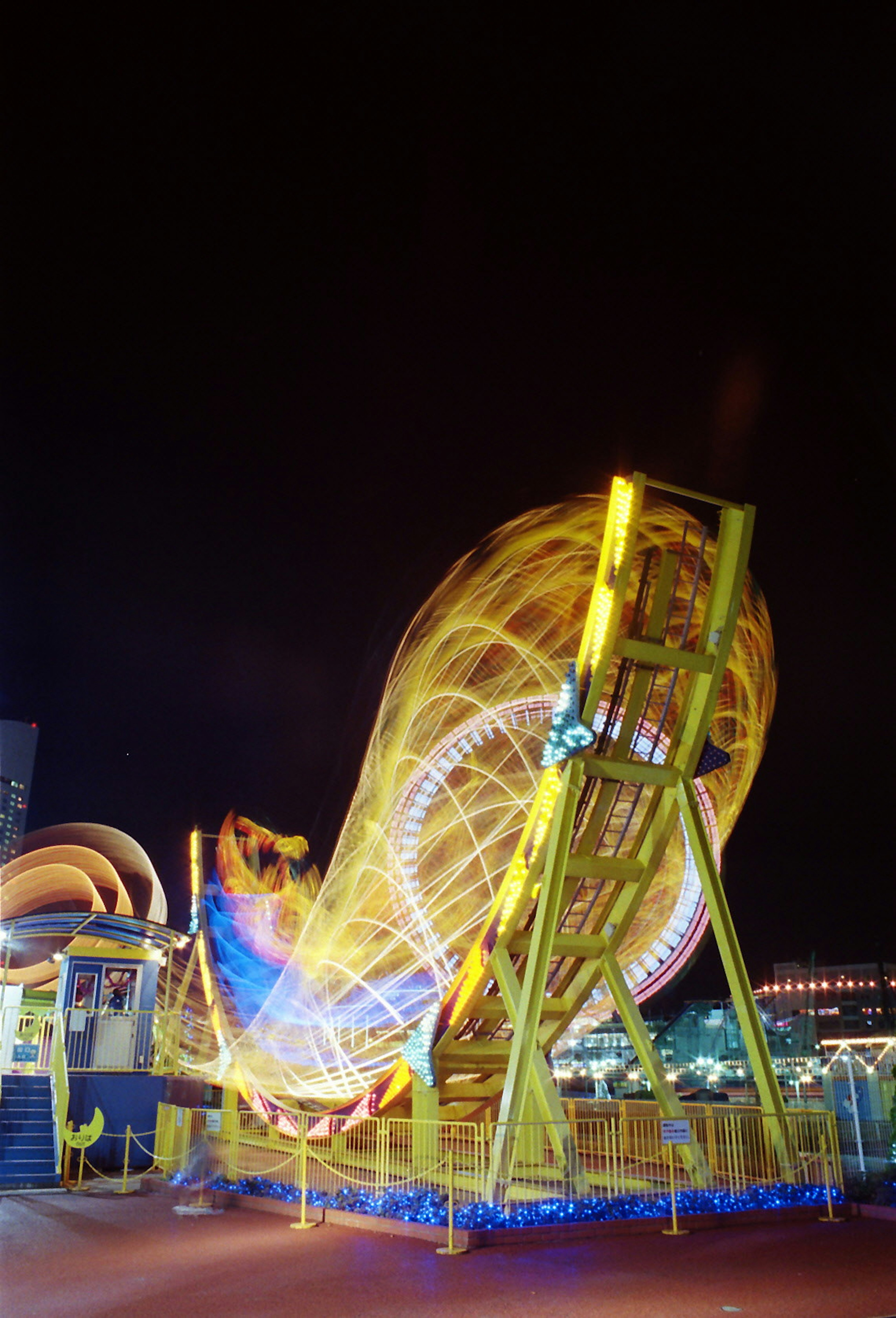 Ferris wheel in motion at night with colorful light trails