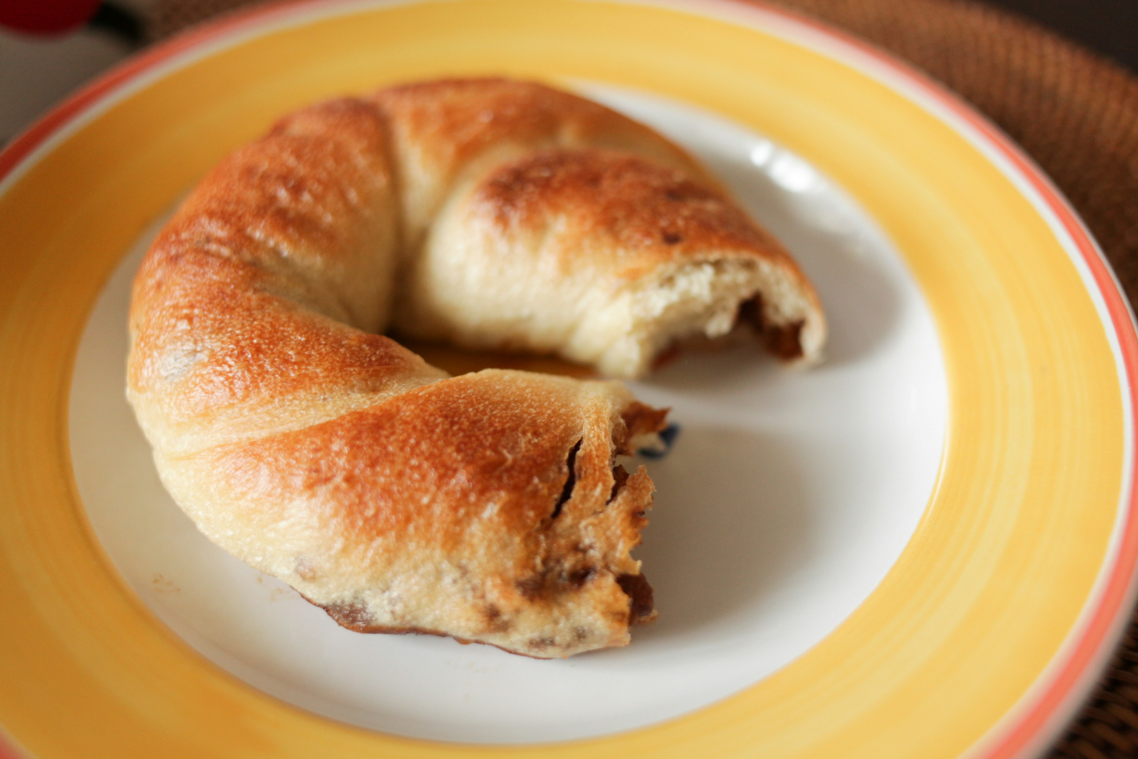 A partially bitten pastry on a yellow and white plate