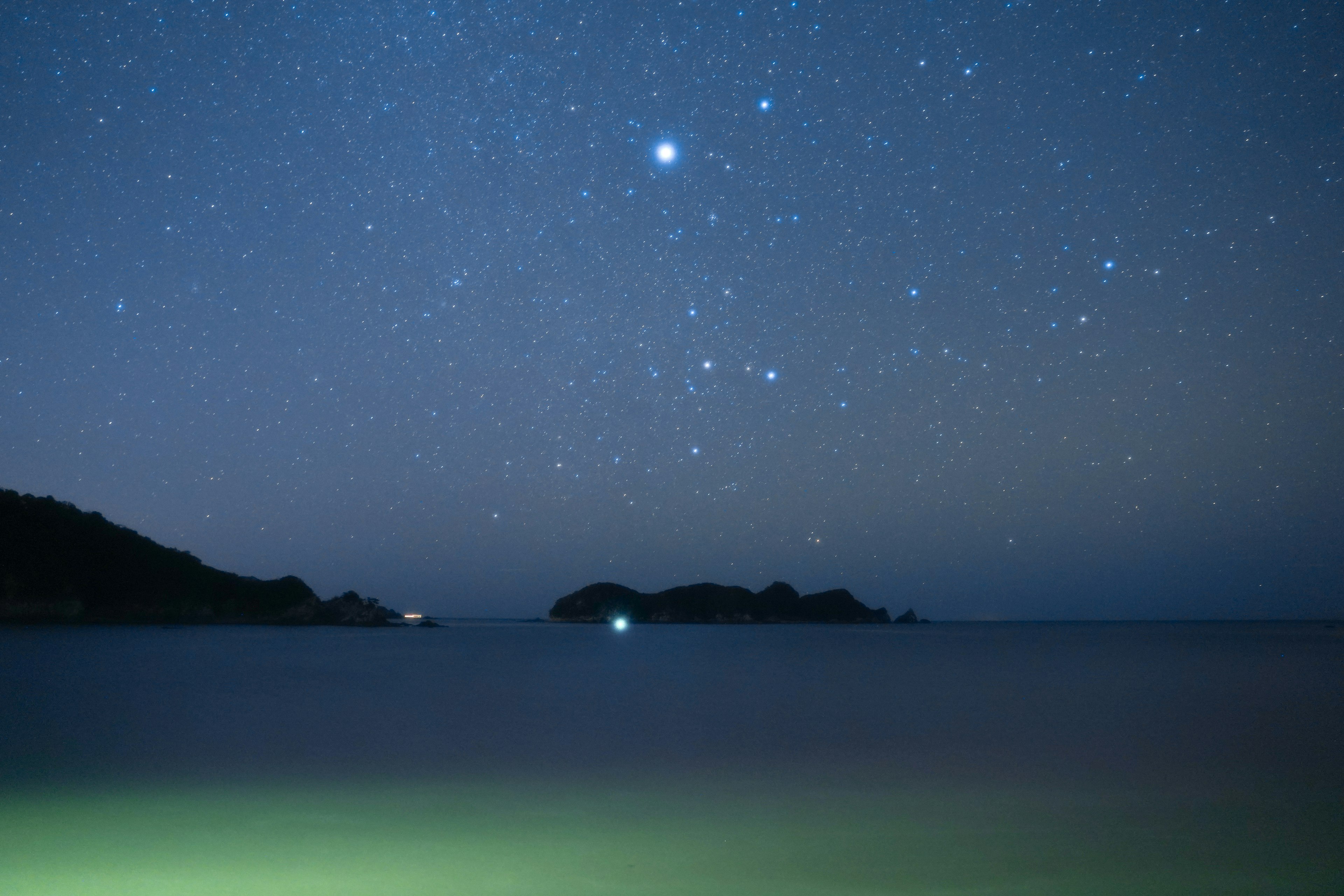 Pemandangan laut malam dengan langit berbintang dan pulau gelap