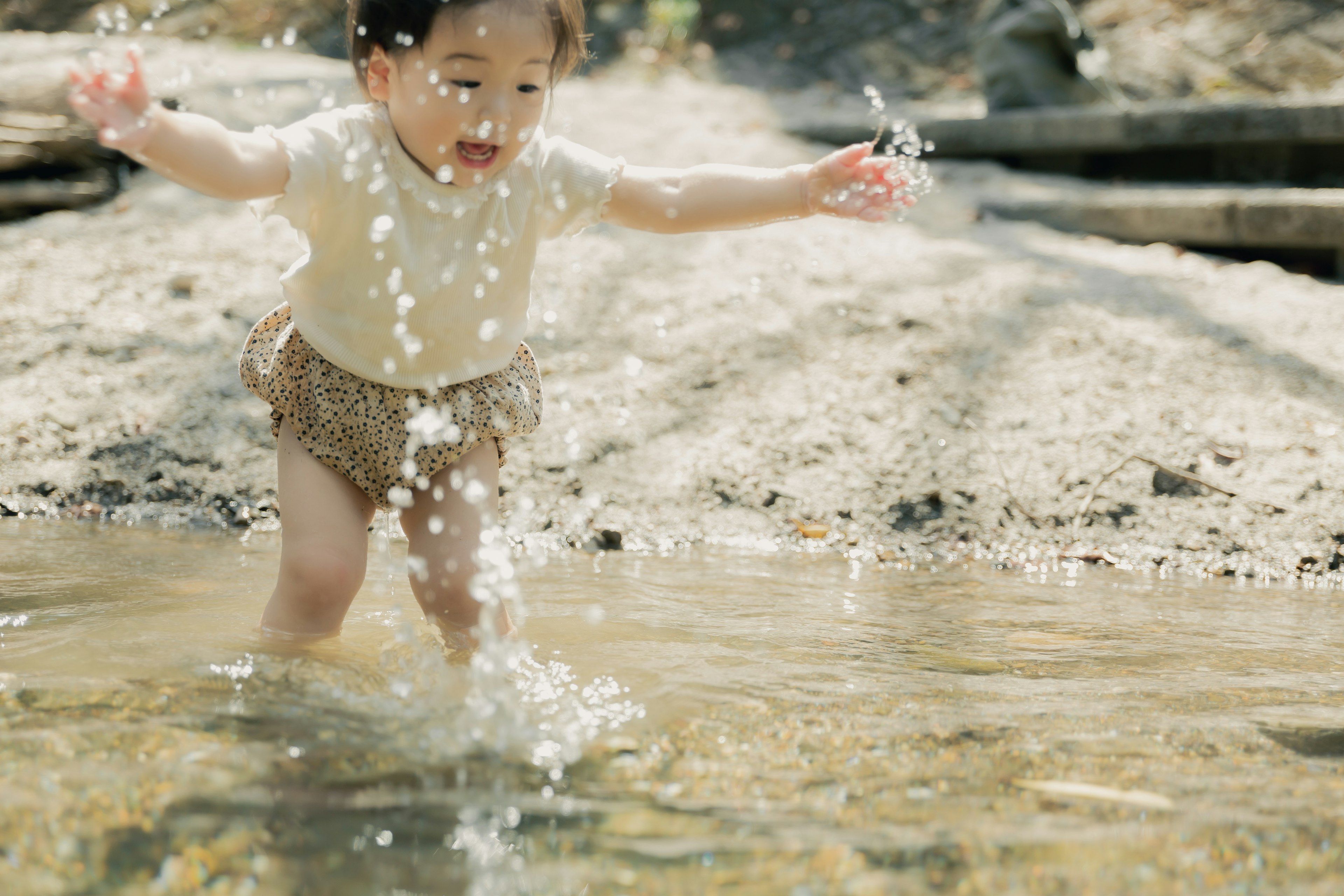 Un bambino che gioca in una pozzanghera spruzzando acqua