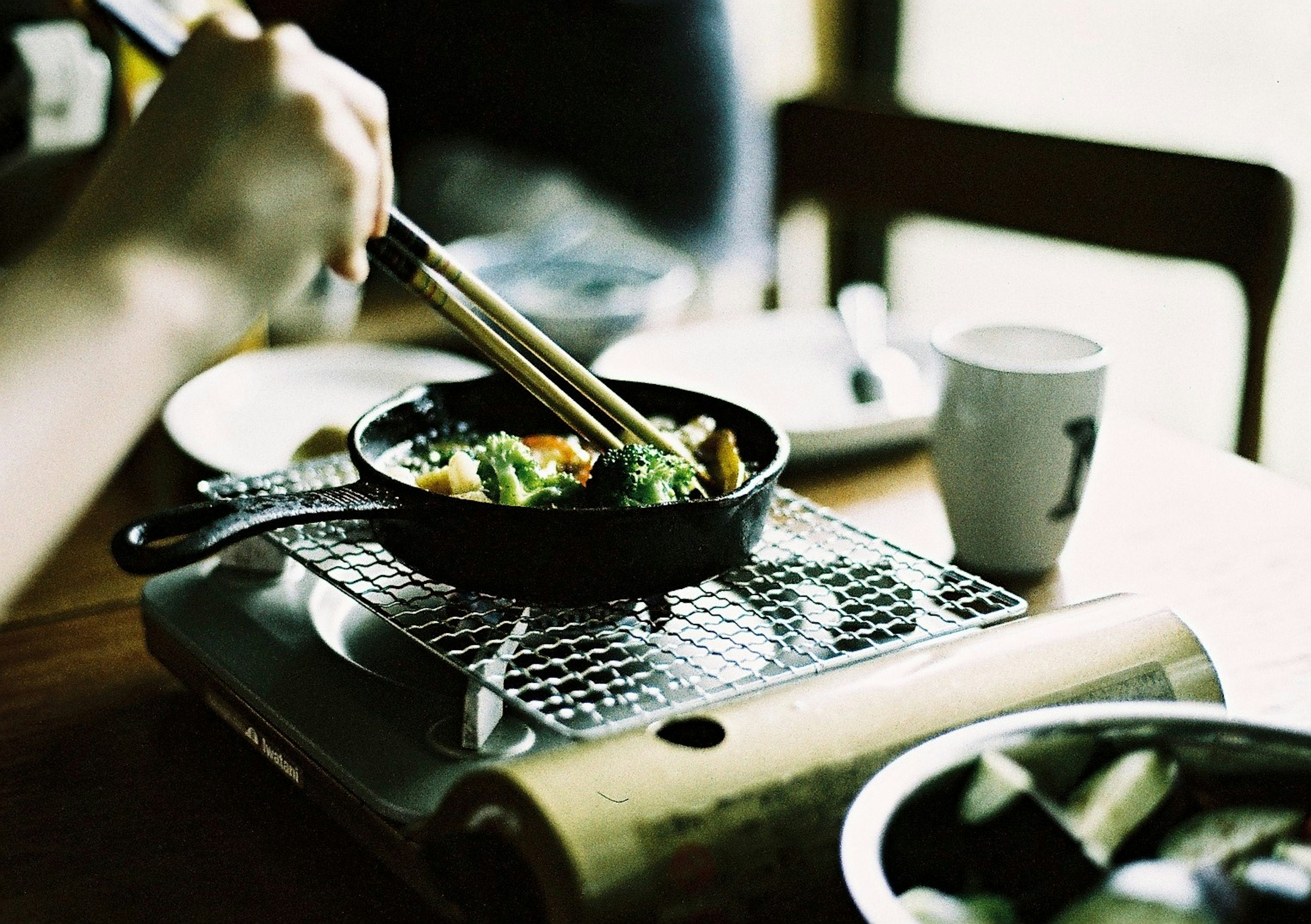 Image of a person using chopsticks to pick food from a skillet