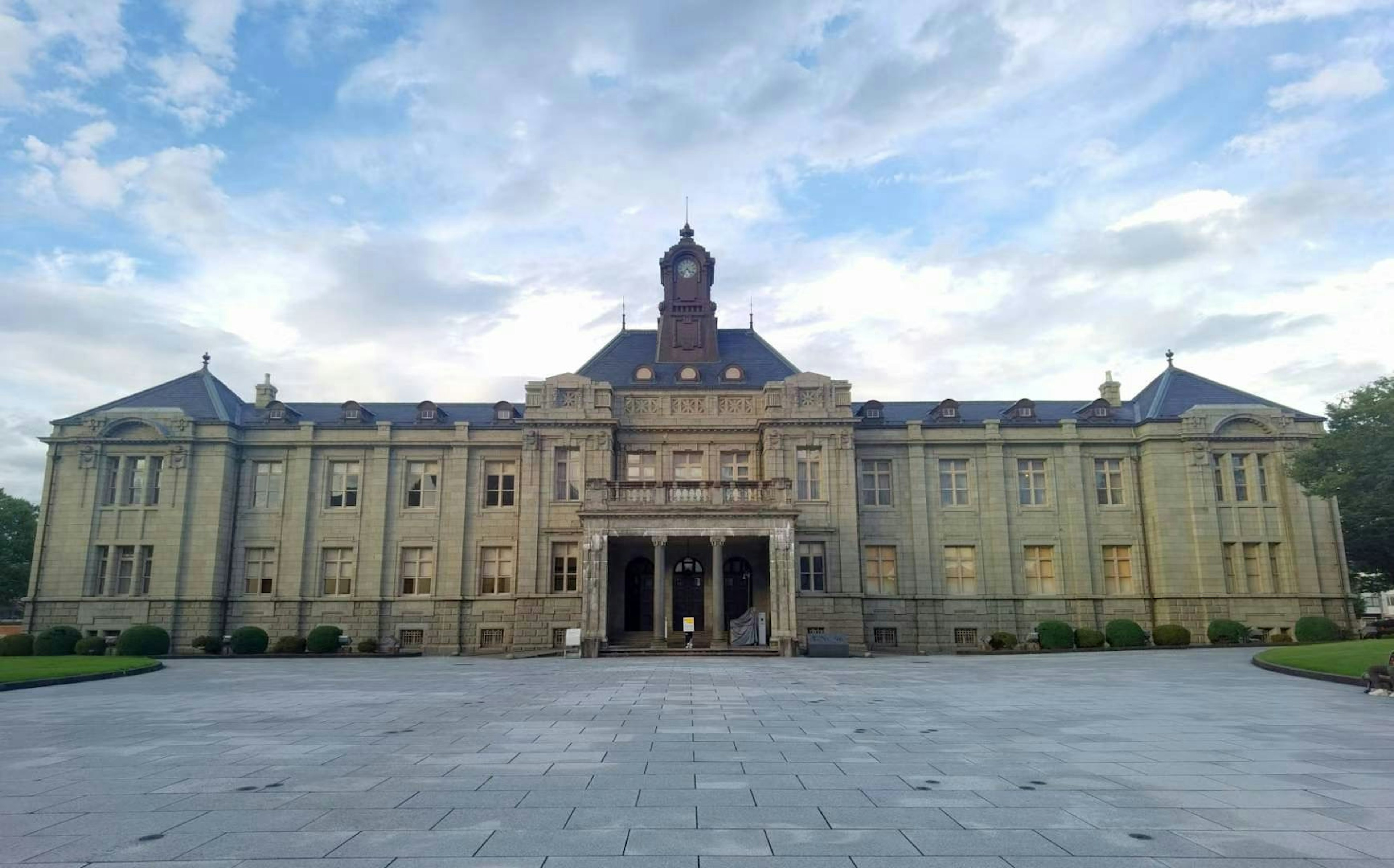 Fassade eines historischen Gebäudes mit grünem Rasen und blauem Himmel im Hintergrund