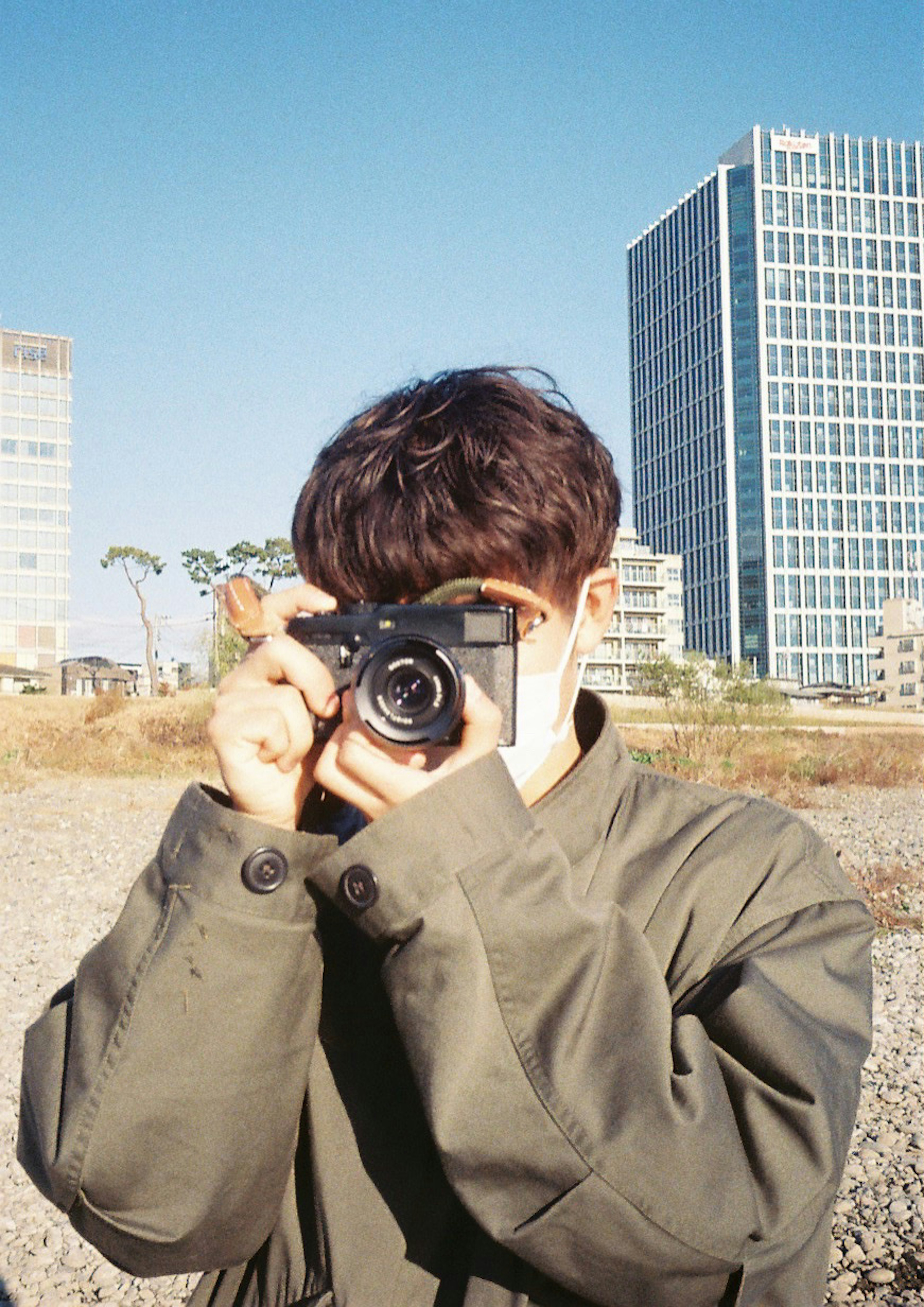 Young man posing with a camera against an urban background