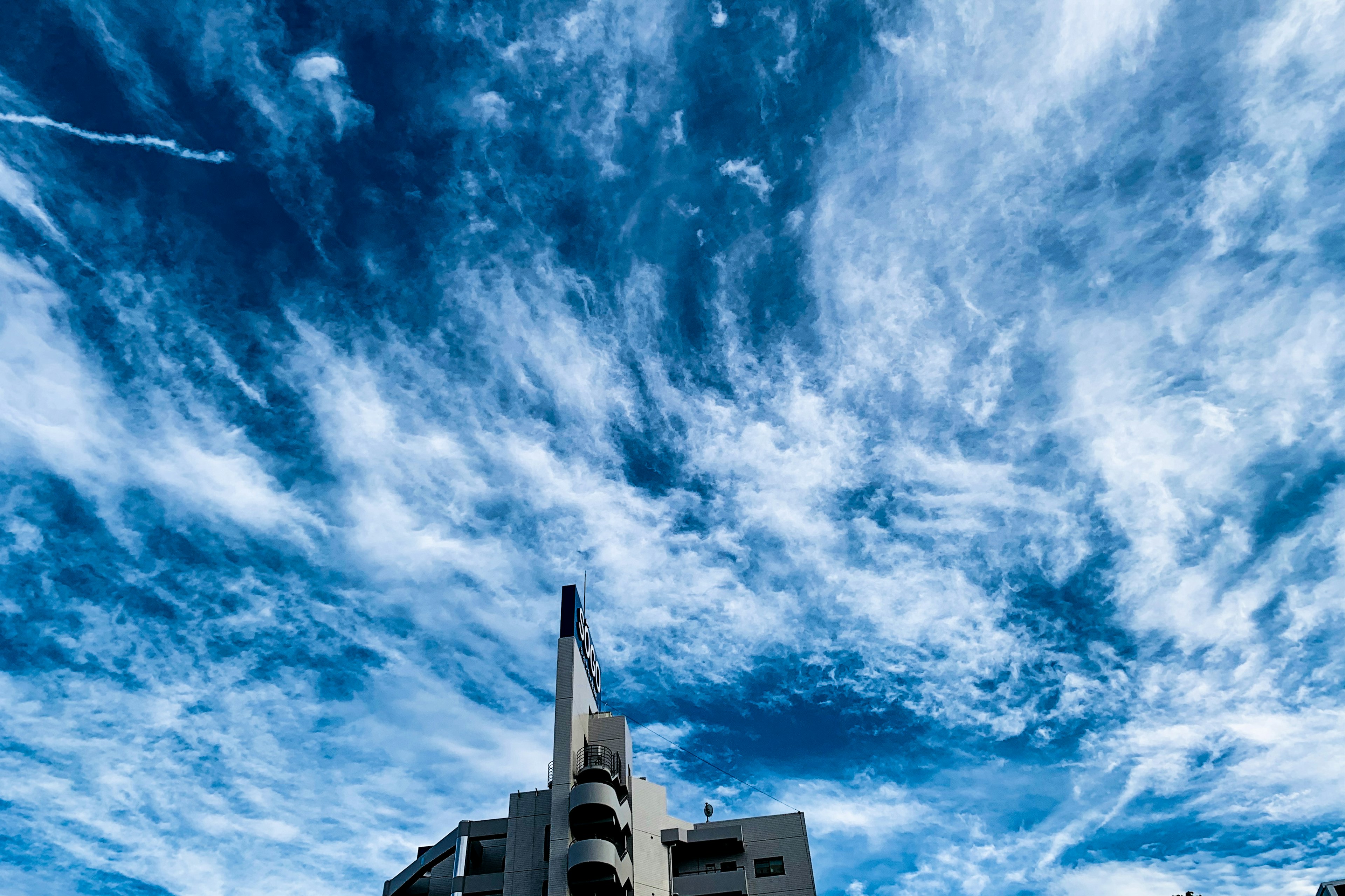 Sky filled with clouds and a view of a building's top