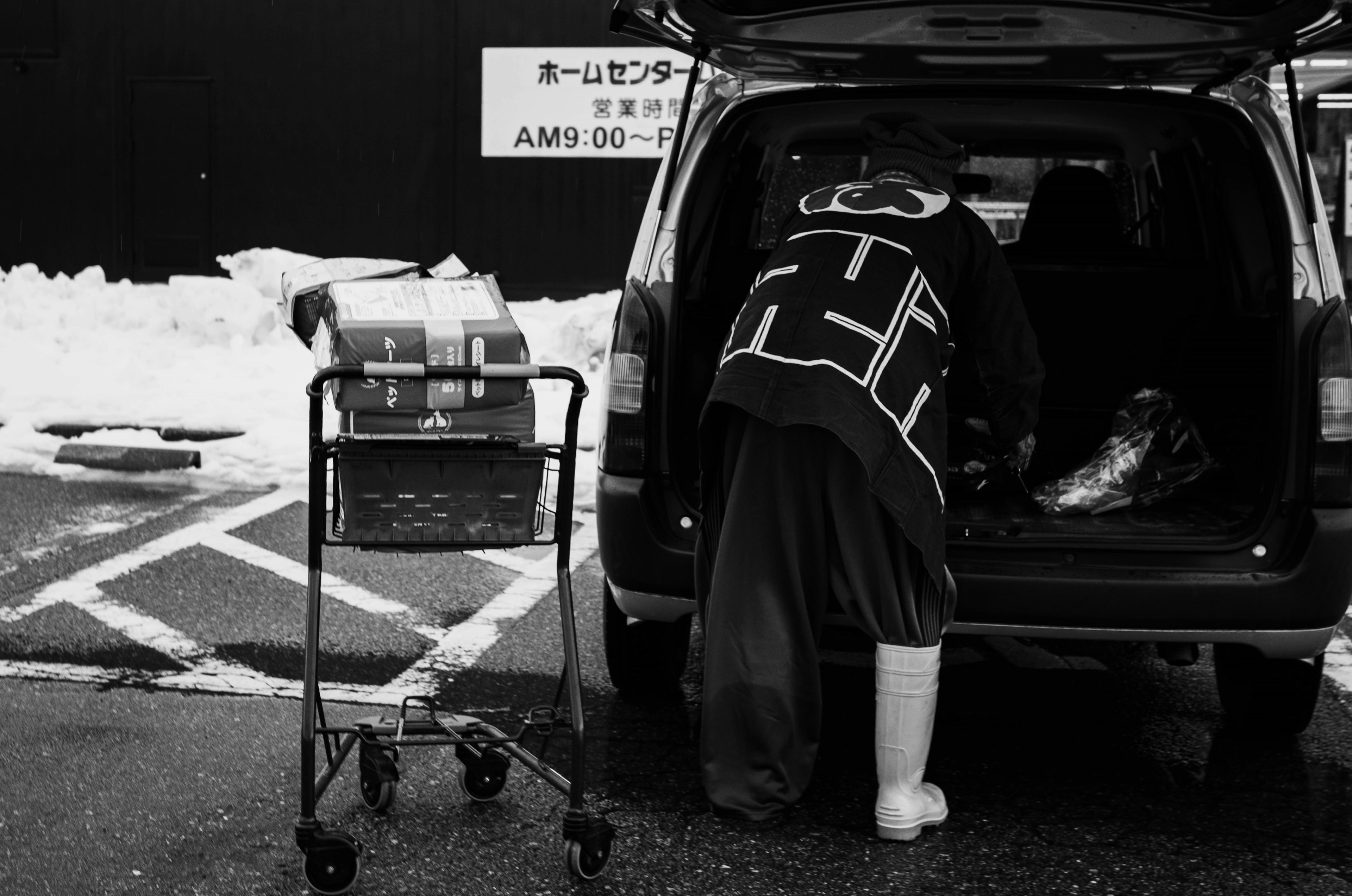 Personne récupérant des articles du coffre de la voiture avec un chariot à proximité