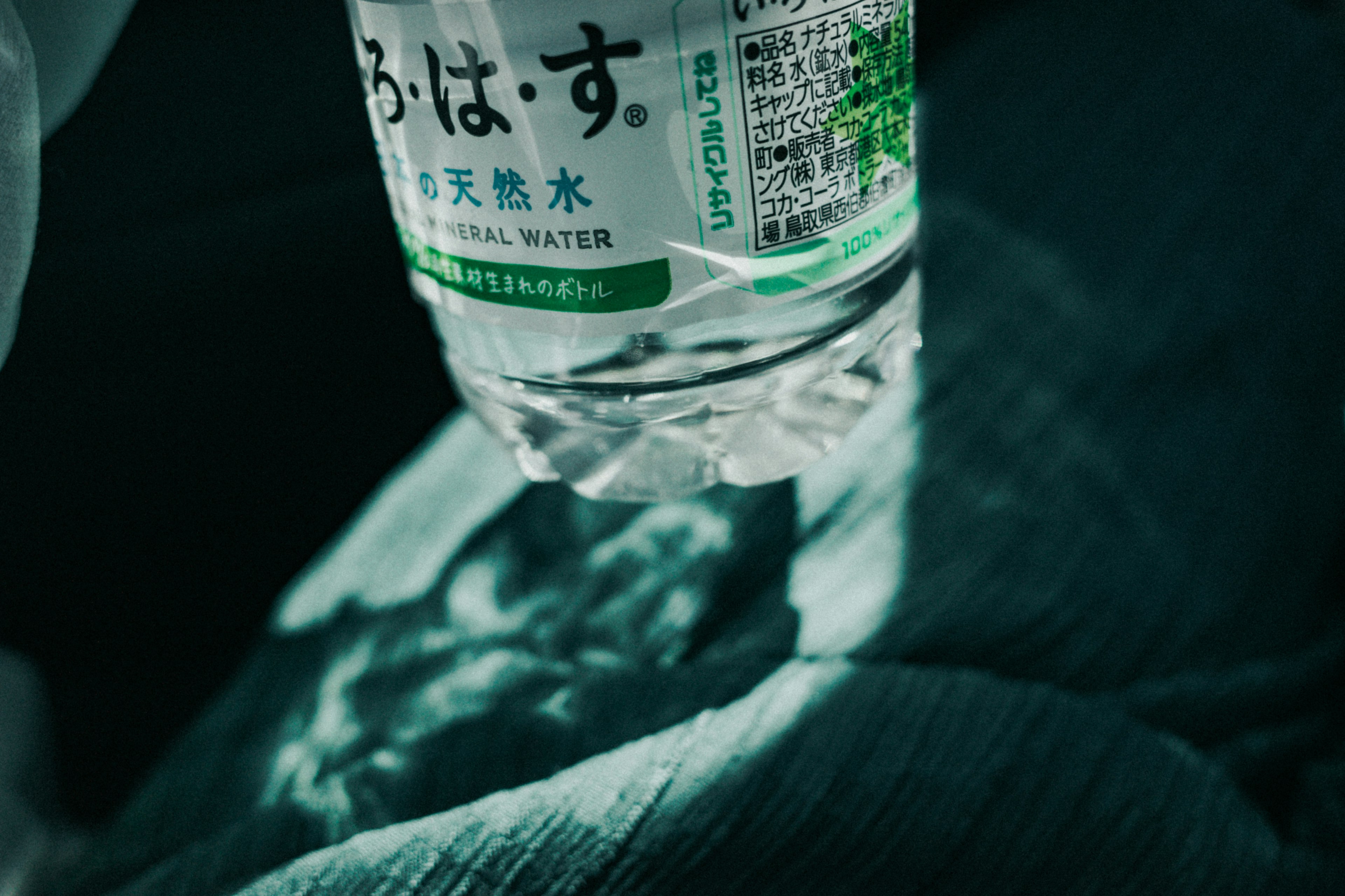 A transparent water bottle resting on green fabric