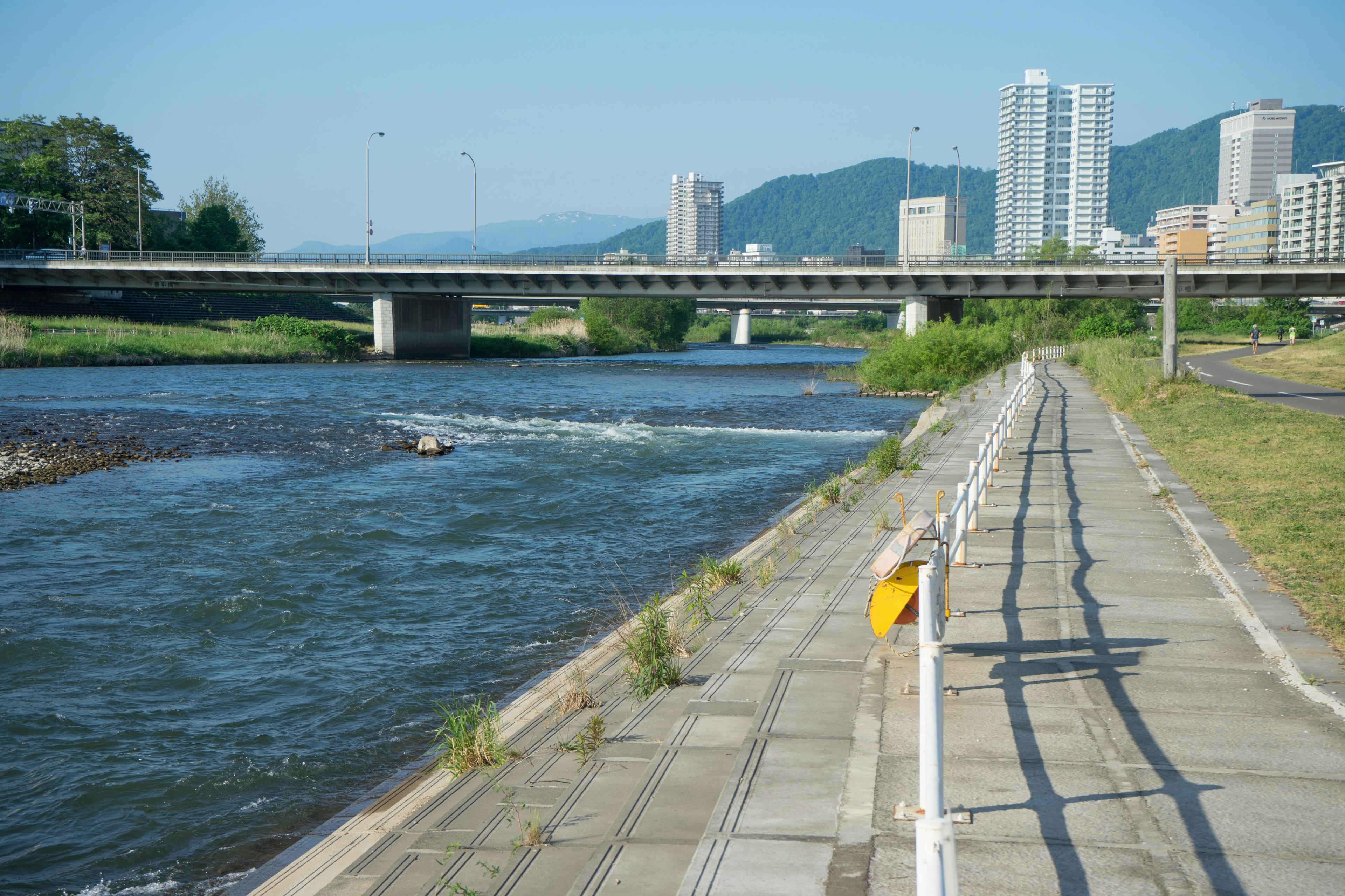 Sendero escénico junto al río con edificios modernos al fondo