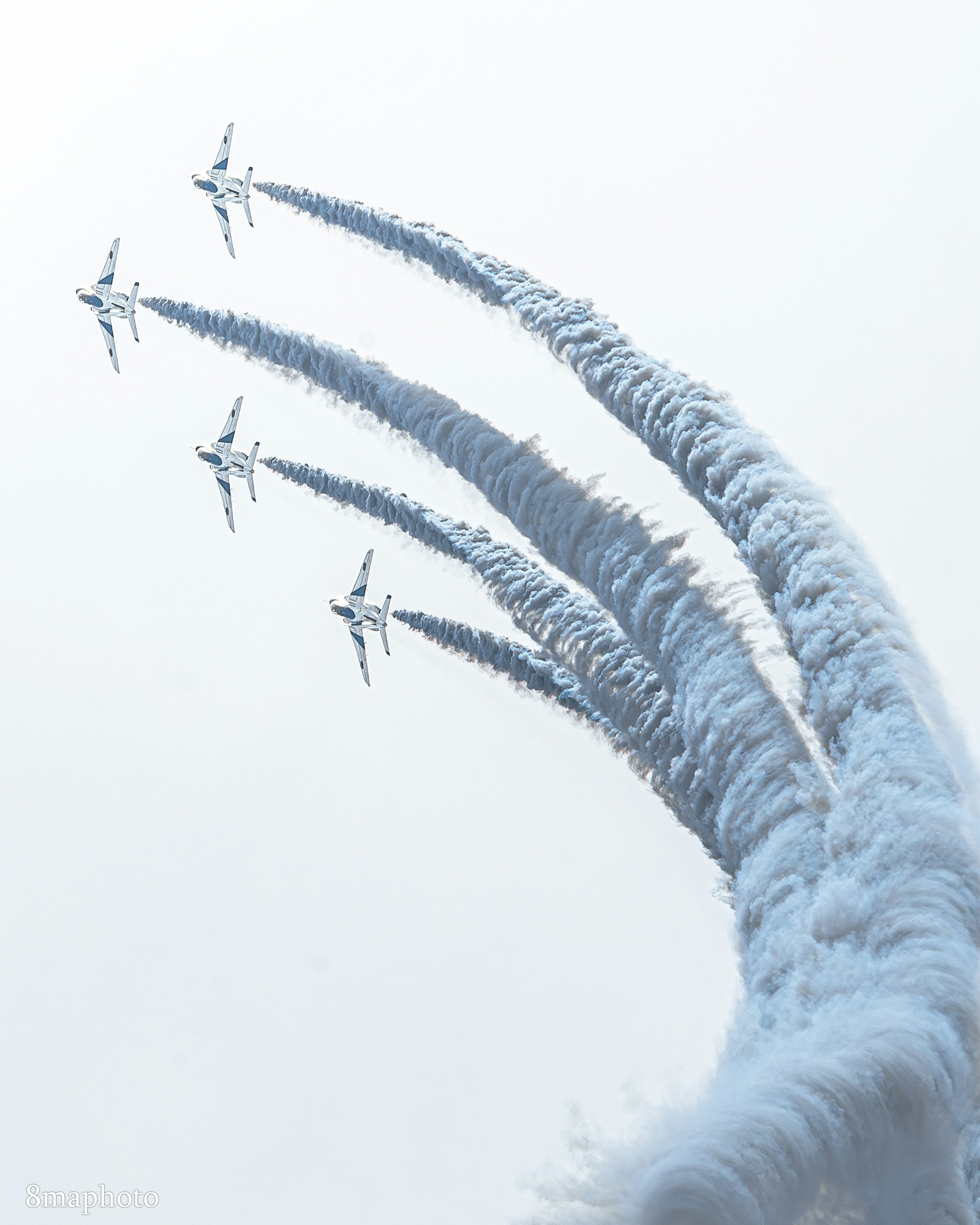 Flugzeugformation mit weißen Rauchspuren vor blauem Himmel