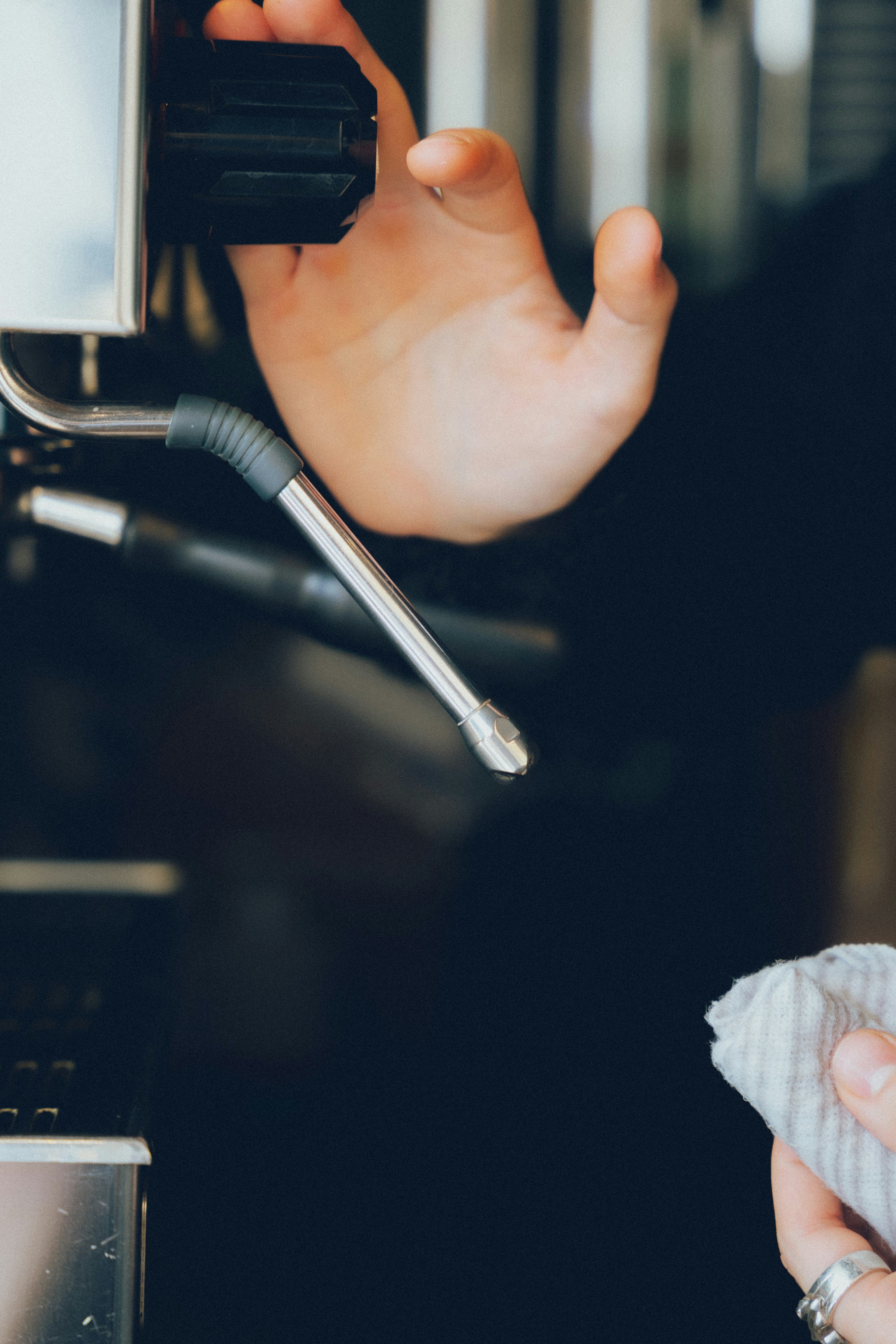 Hand bedient die Dampfdüse einer Kaffeemaschine