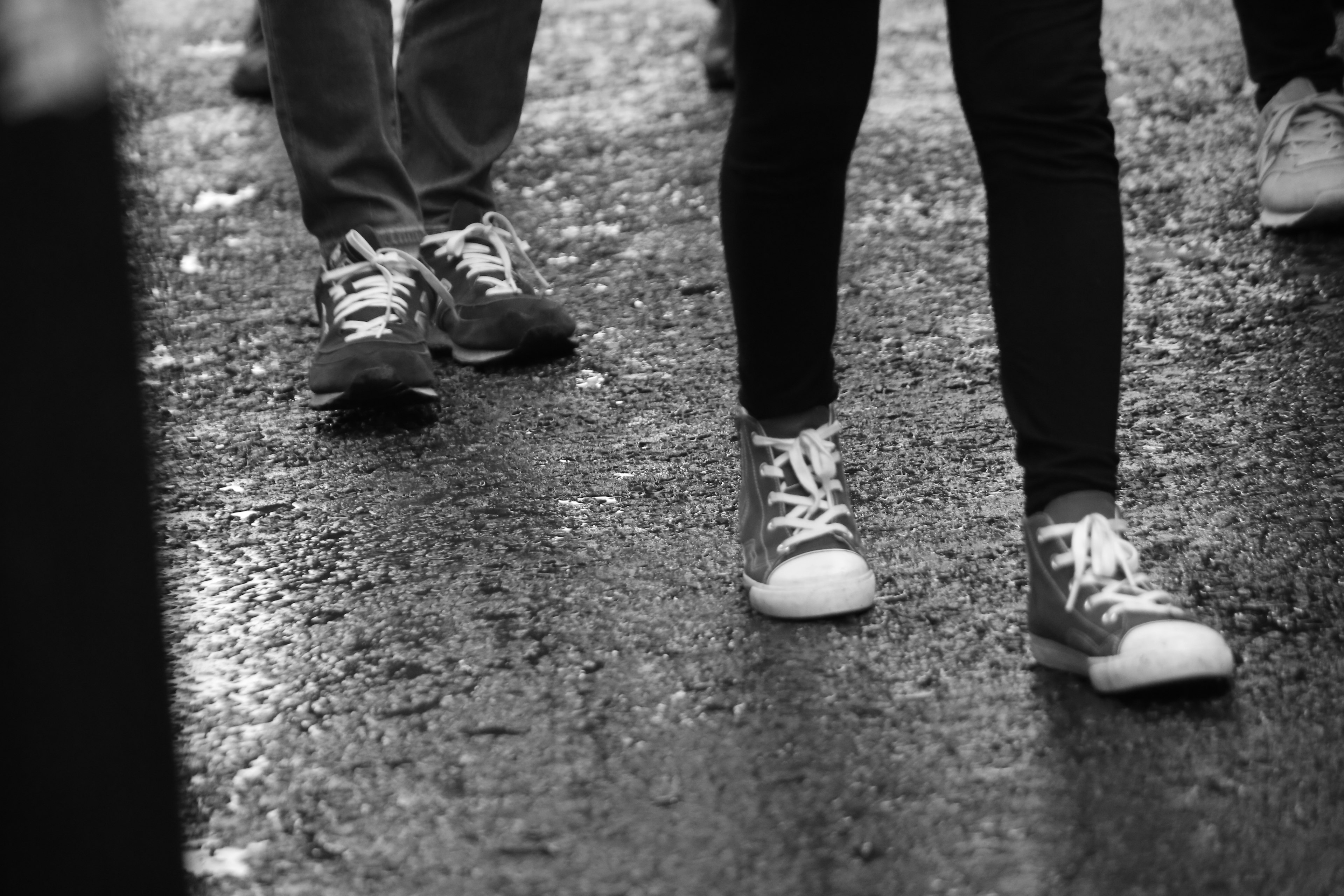 Foto en blanco y negro de dos pares de pies caminando sobre una calle mojada