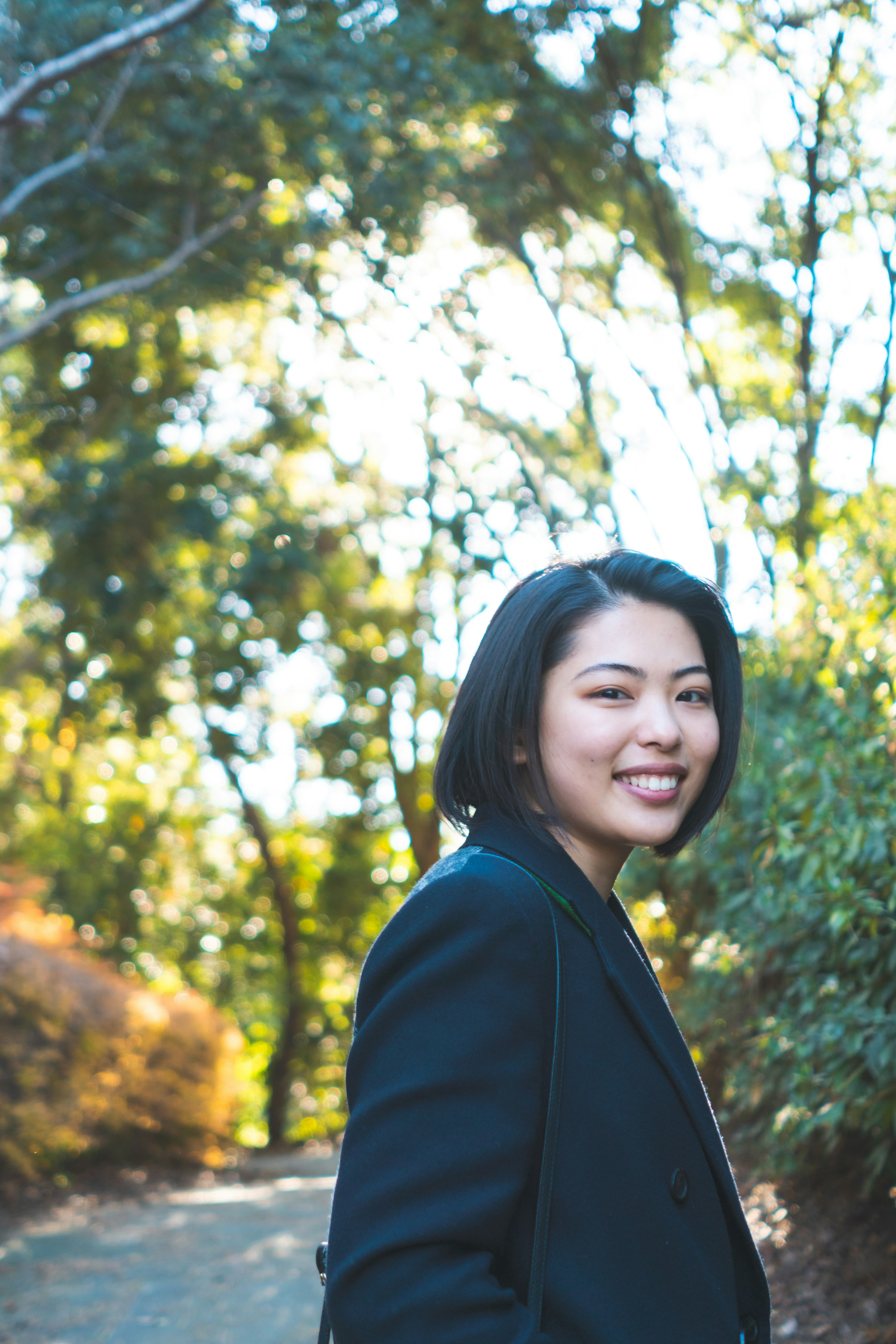 Smiling woman in profile surrounded by greenery and bright background