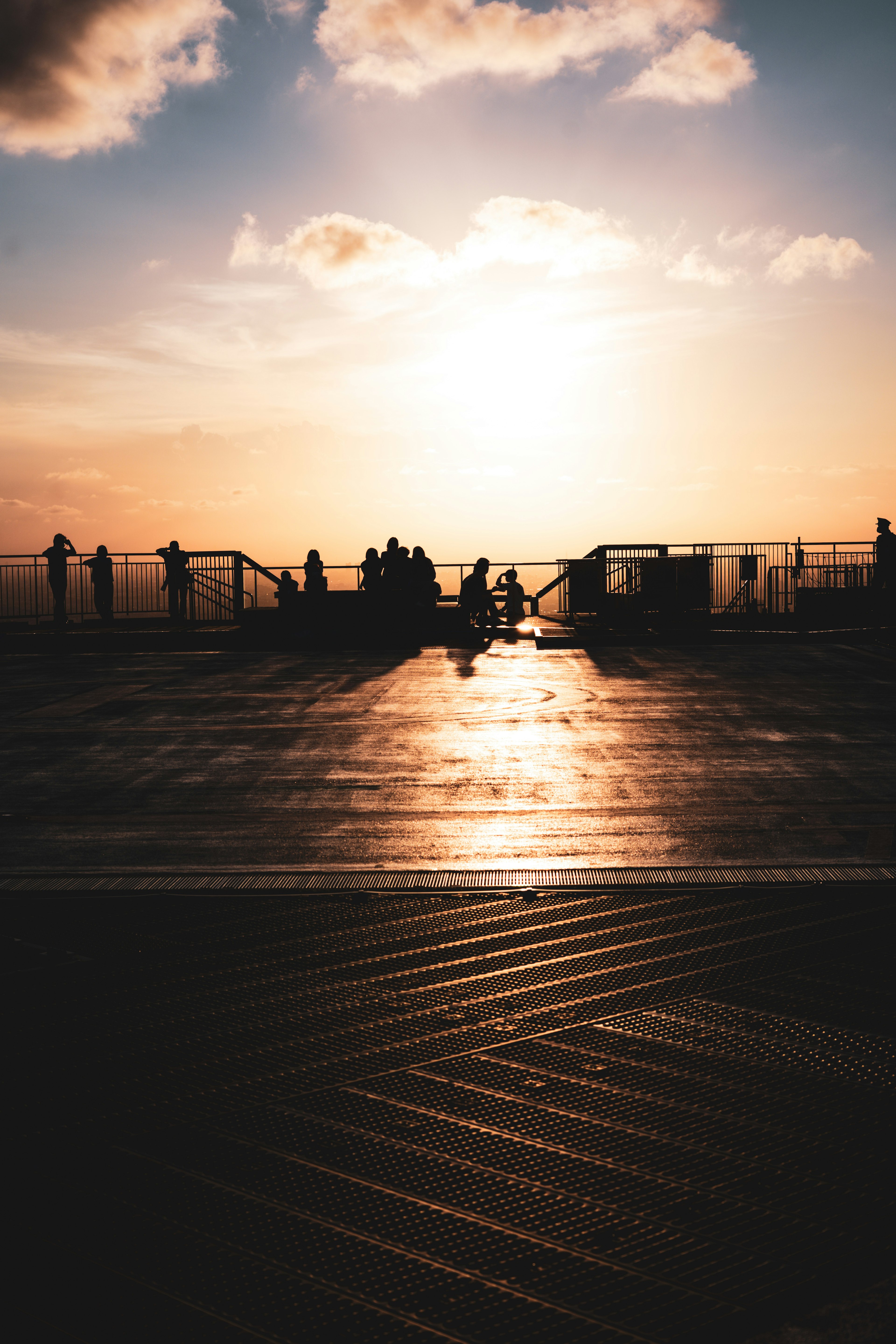 Silhouettes of people sitting against a sunset with reflections on wooden flooring