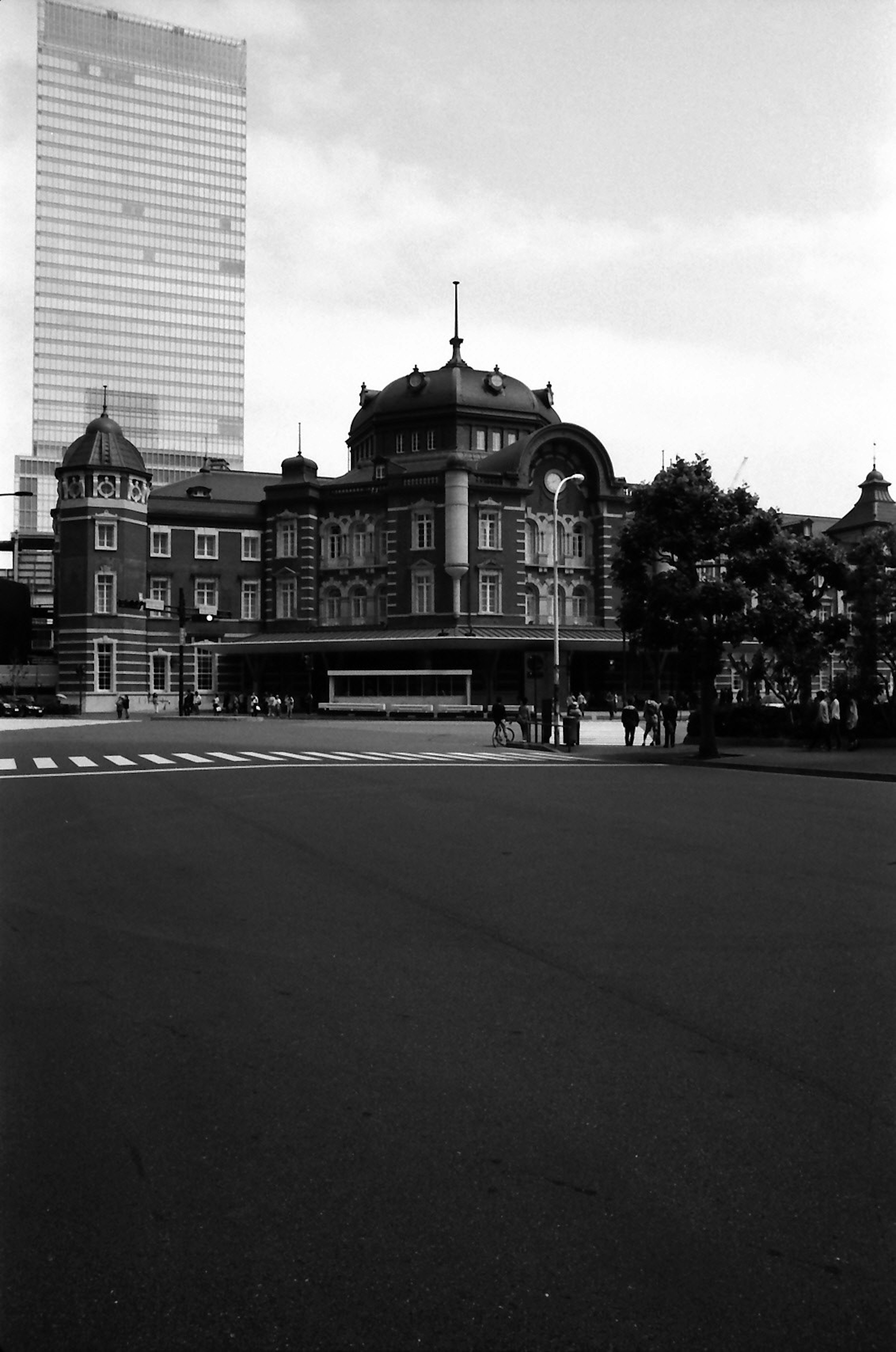 Foto en blanco y negro que contrasta el edificio histórico de la estación de Tokio con un rascacielos moderno