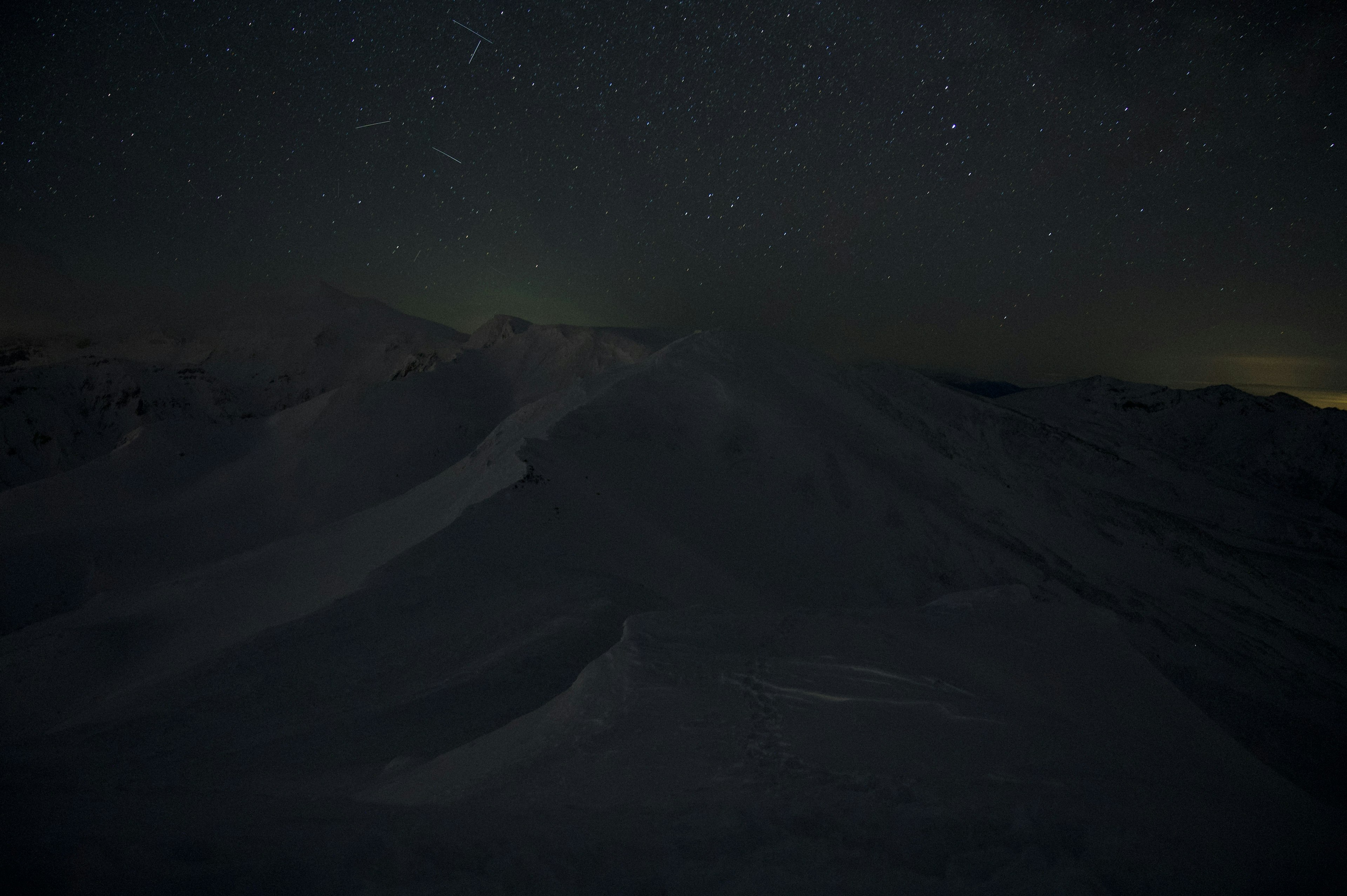 雪山と星空の風景が広がる暗い夜