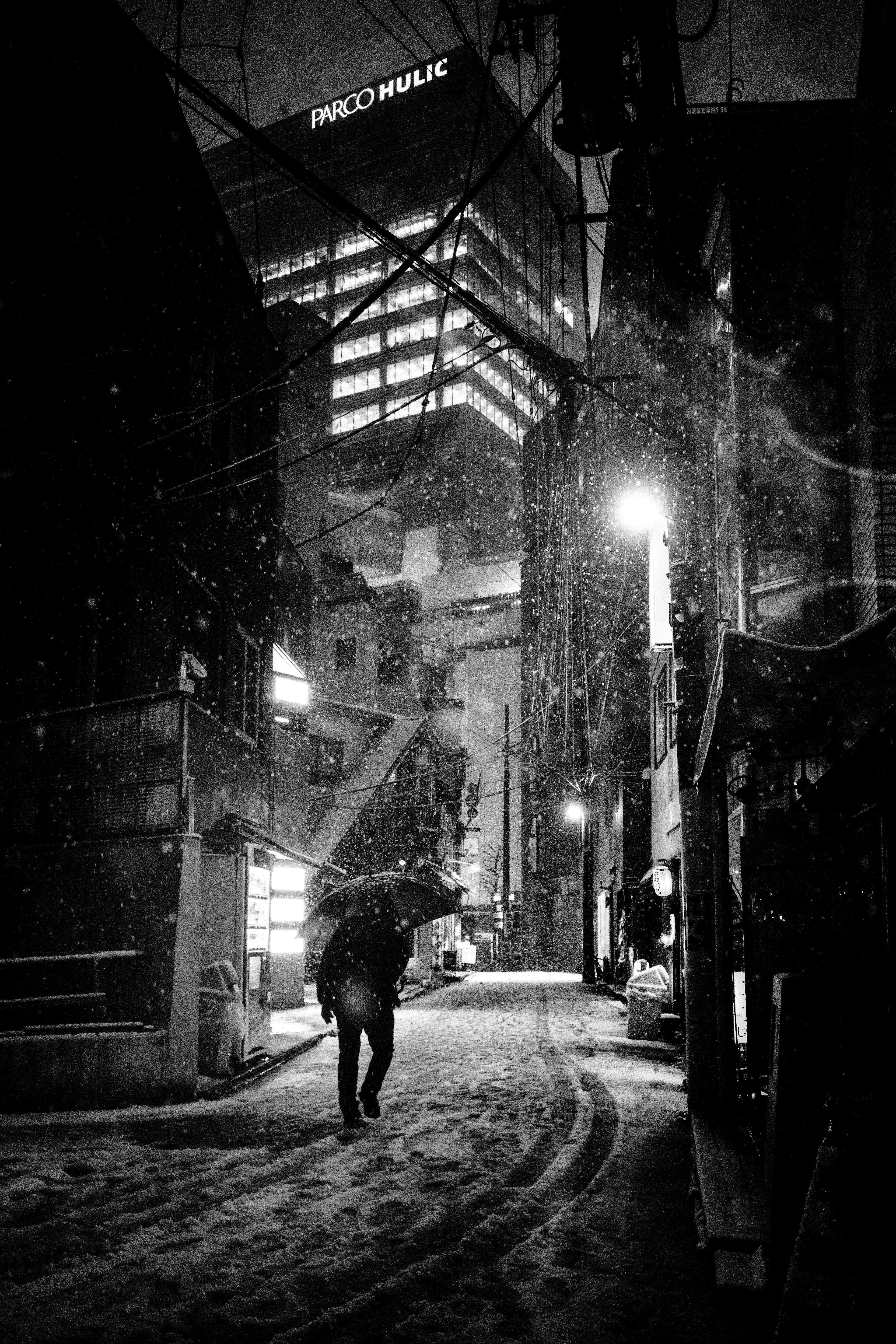 Una silhouette che cammina in un vicolo innevato di notte