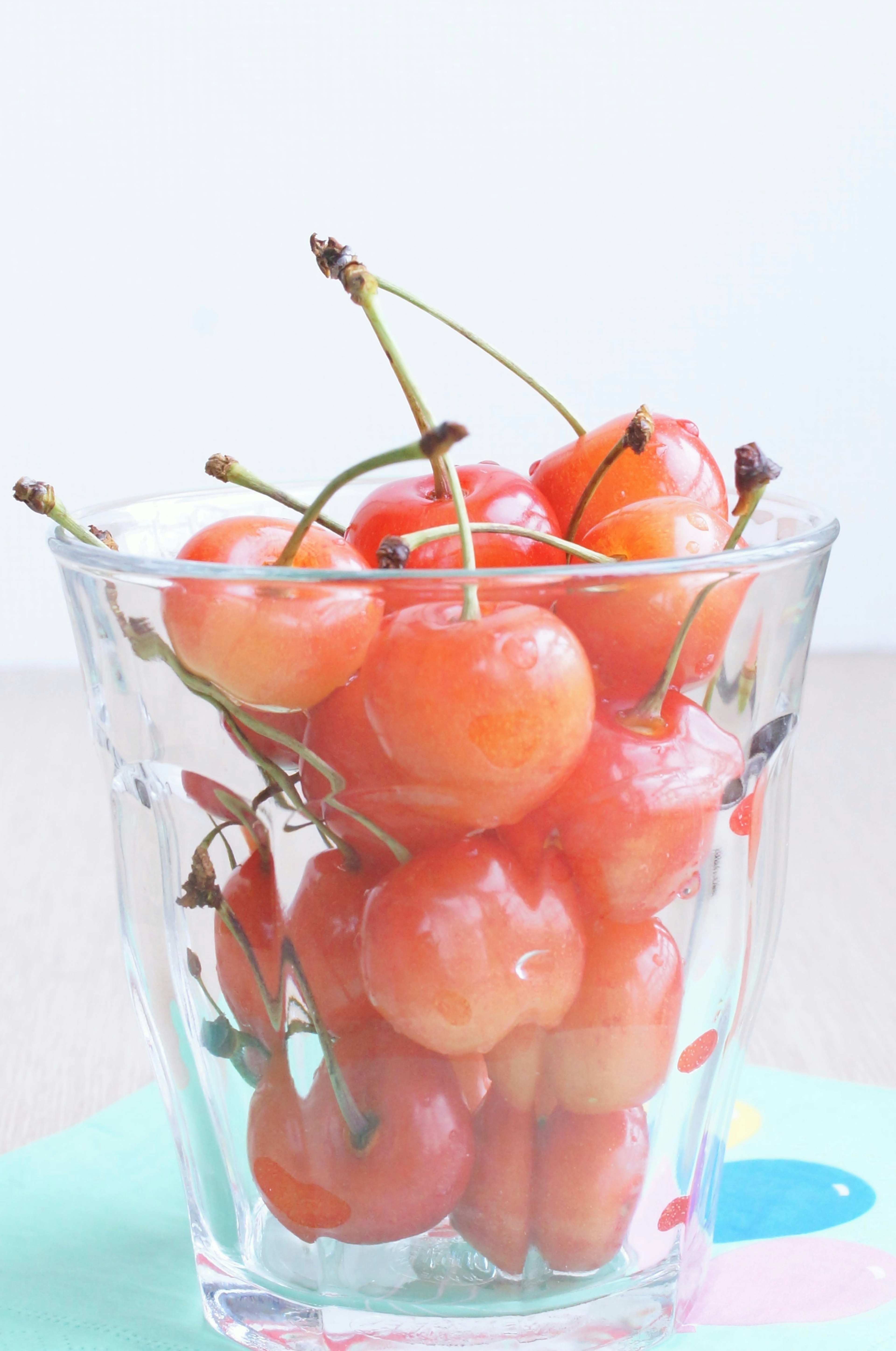 Un vaso transparente lleno de cerezas rojas que muestran su color vibrante