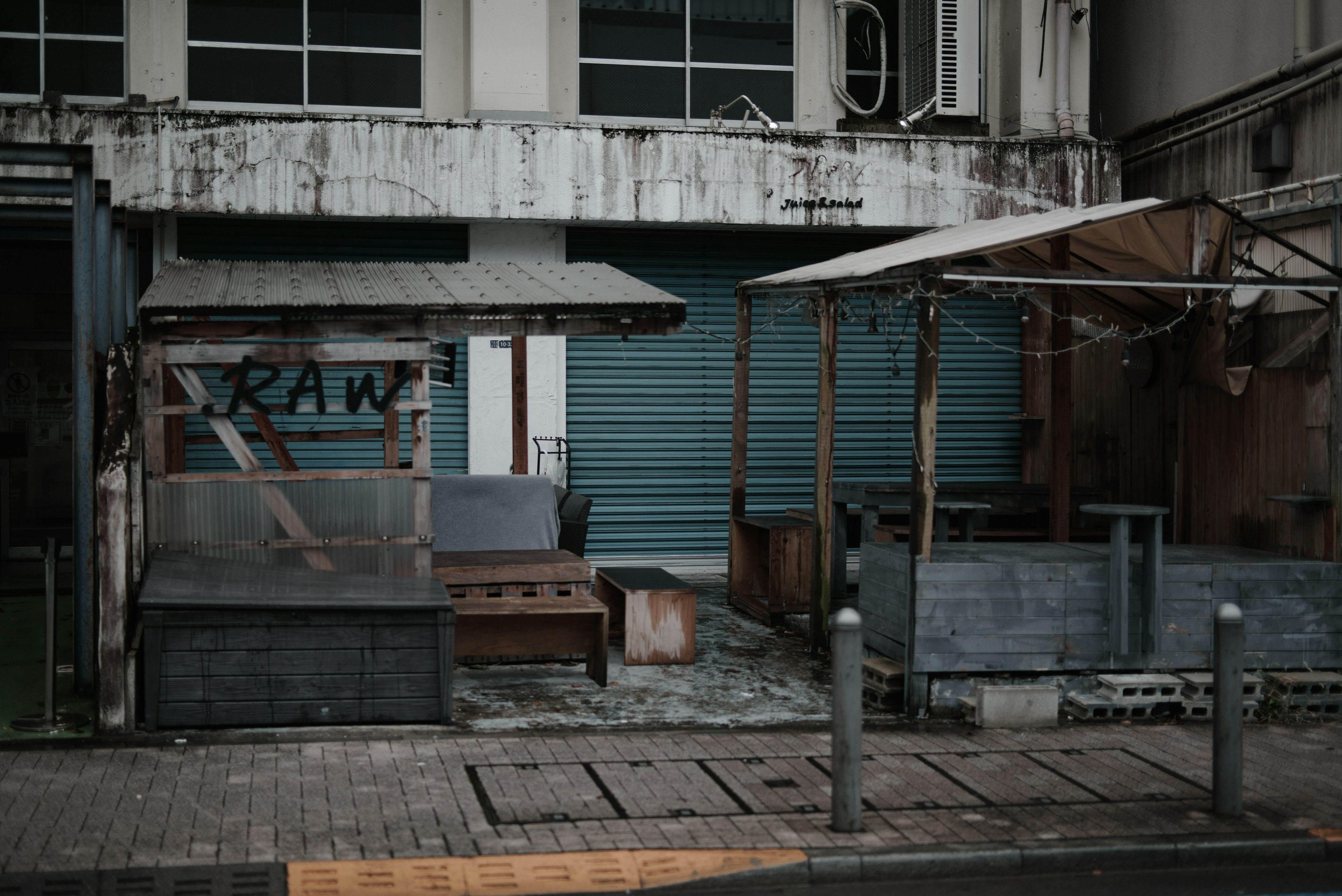 Exterior of an old commercial building with blue shutter and weathered wooden stalls