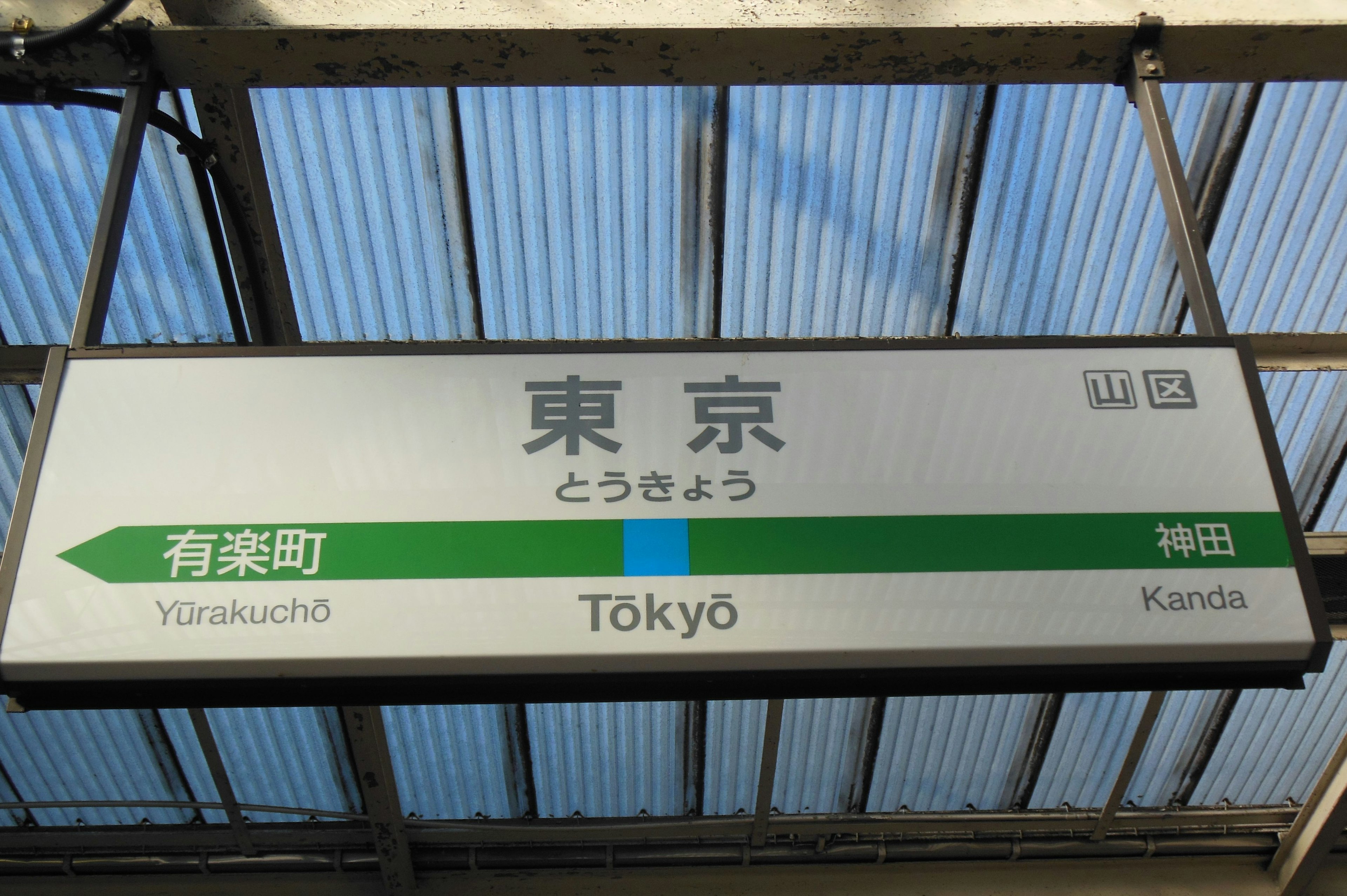 Sign for Tokyo Station featuring green arrow and station names