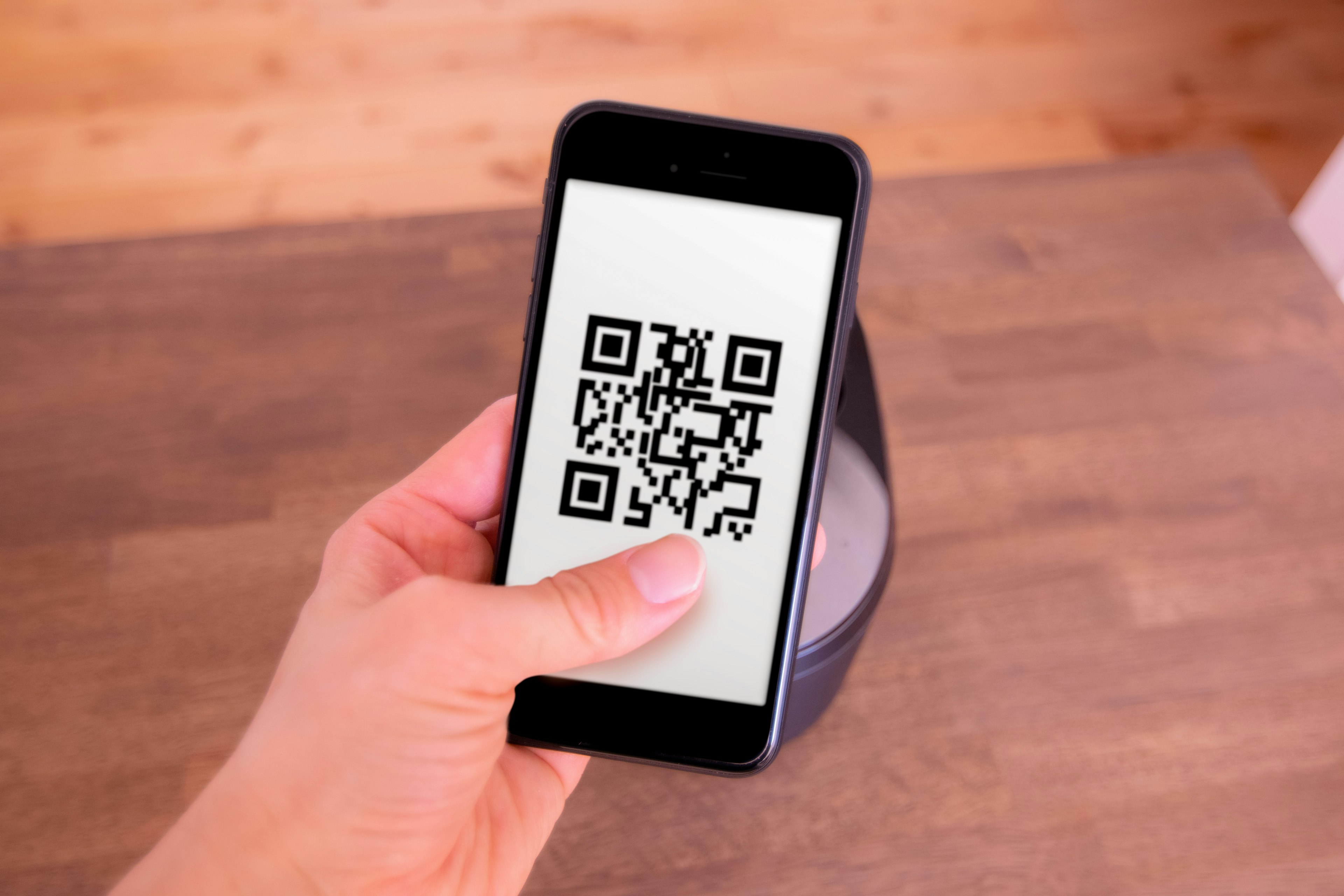 Smartphone displaying a QR code held in a hand