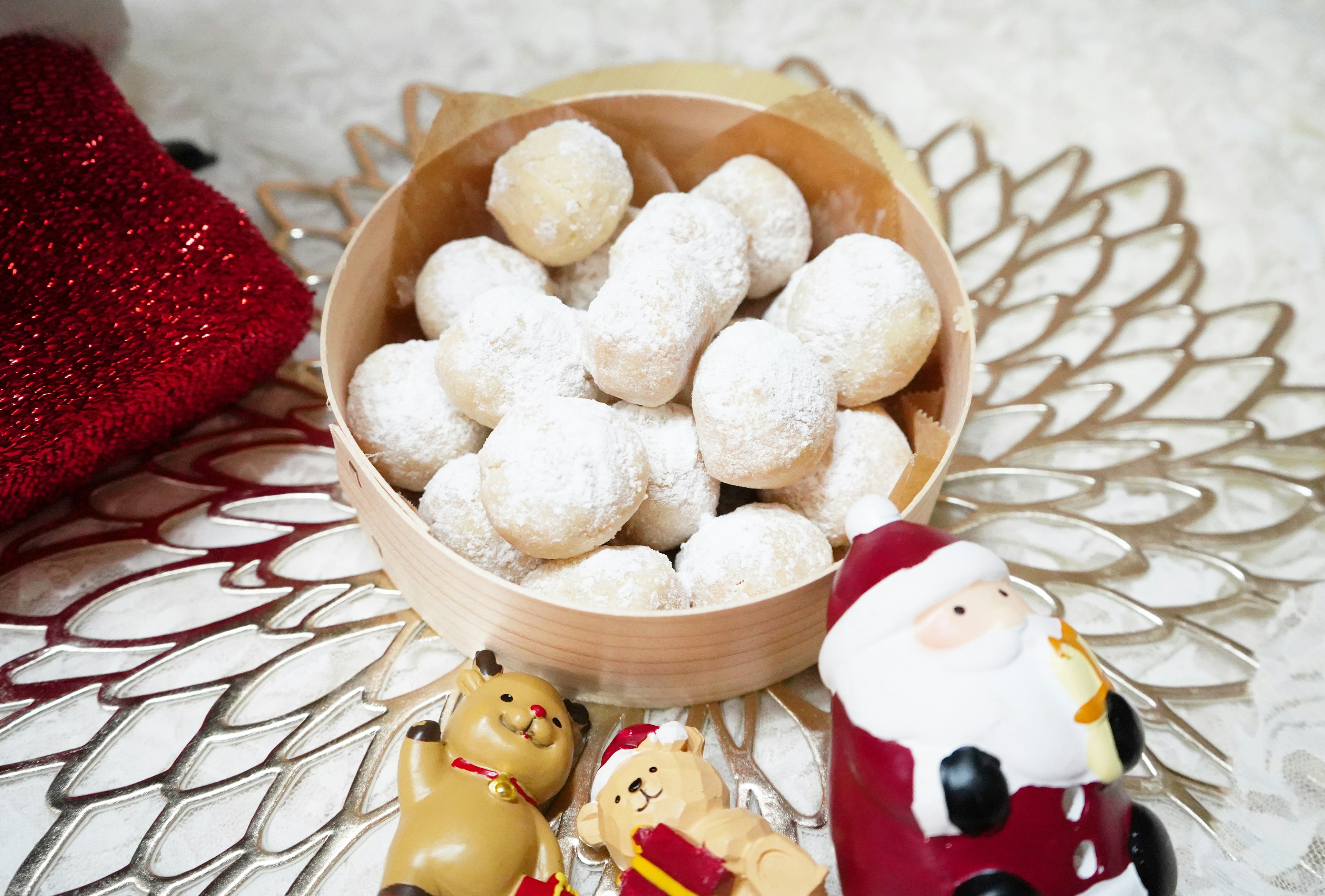 Bowl of powdered sugar dusted cookies surrounded by Christmas decorations