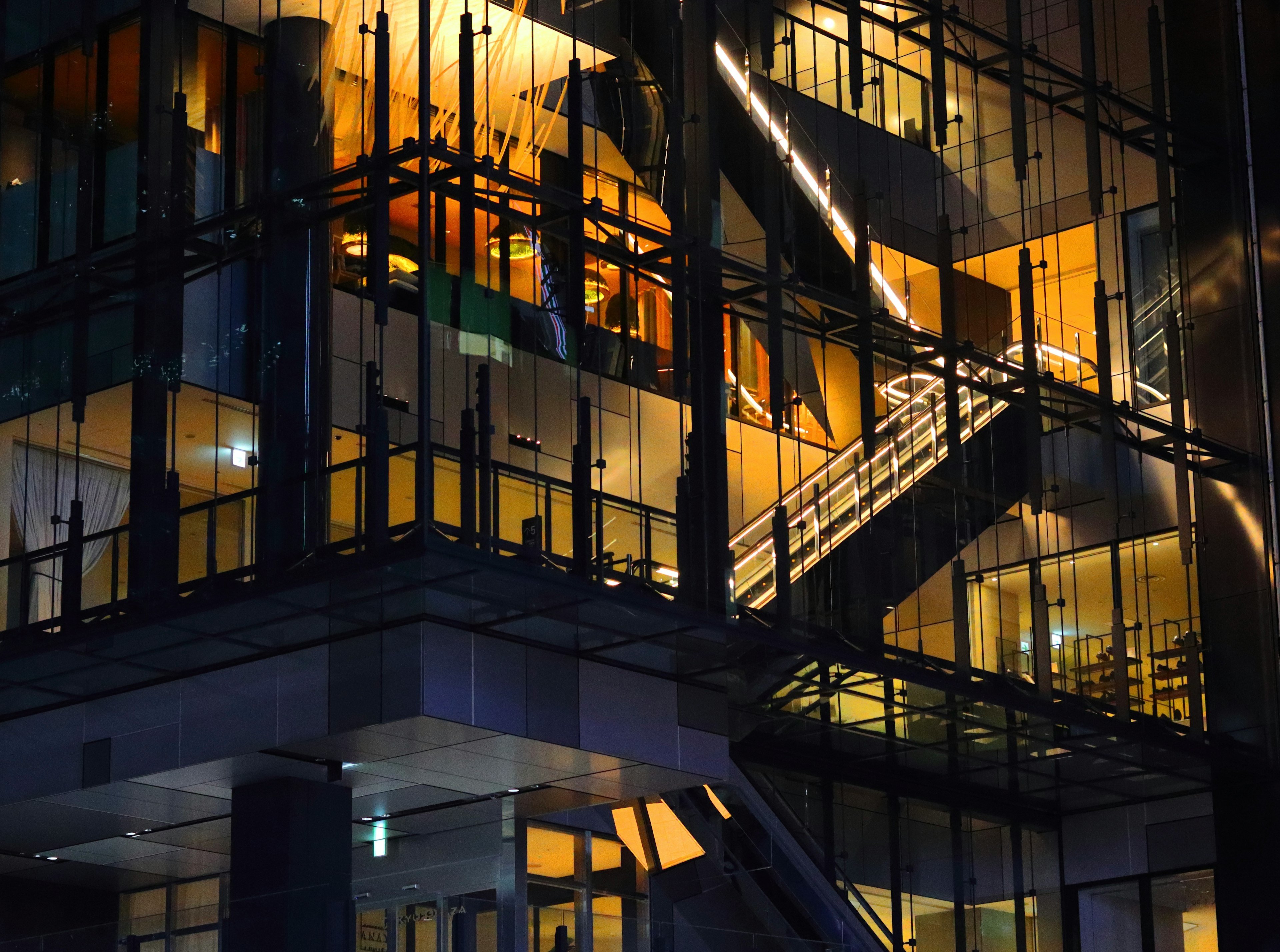 Edificio moderno de noche con fachada de vidrio y escalera prominente