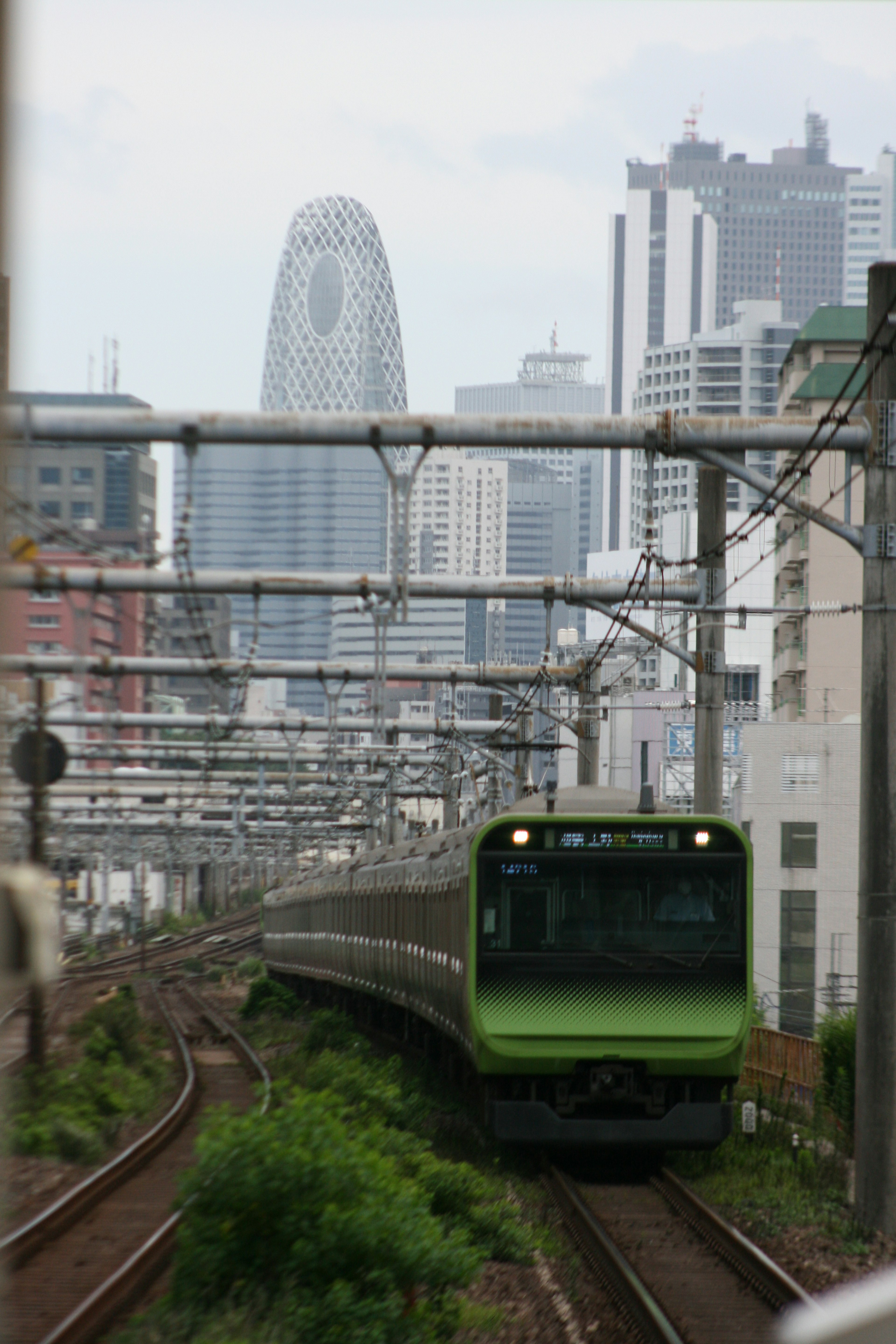 緑色の電車が都市の高層ビルを背景に走行している風景