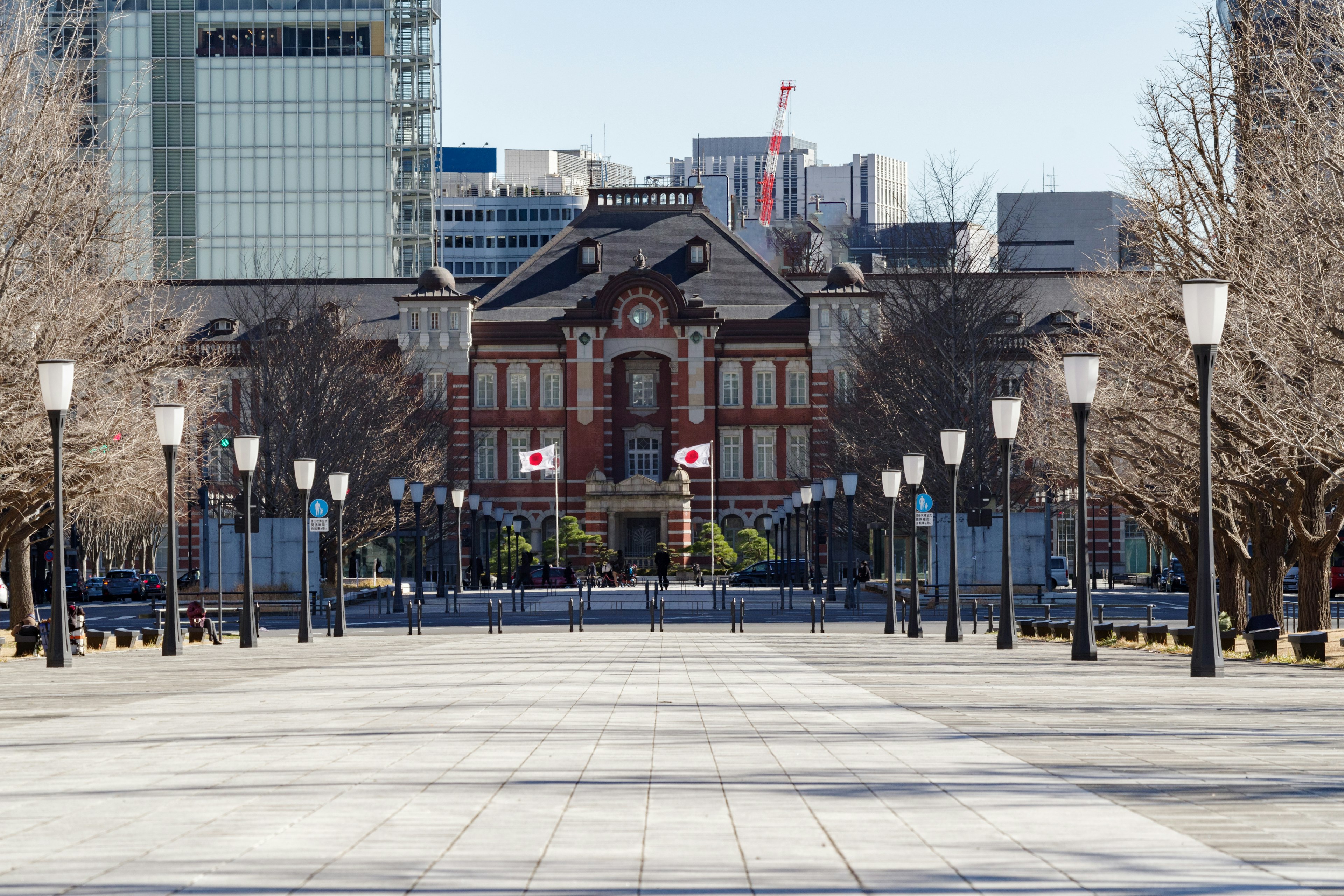 Gare de Tokyo avec une architecture en briques rouges et une allée bordée d'arbres