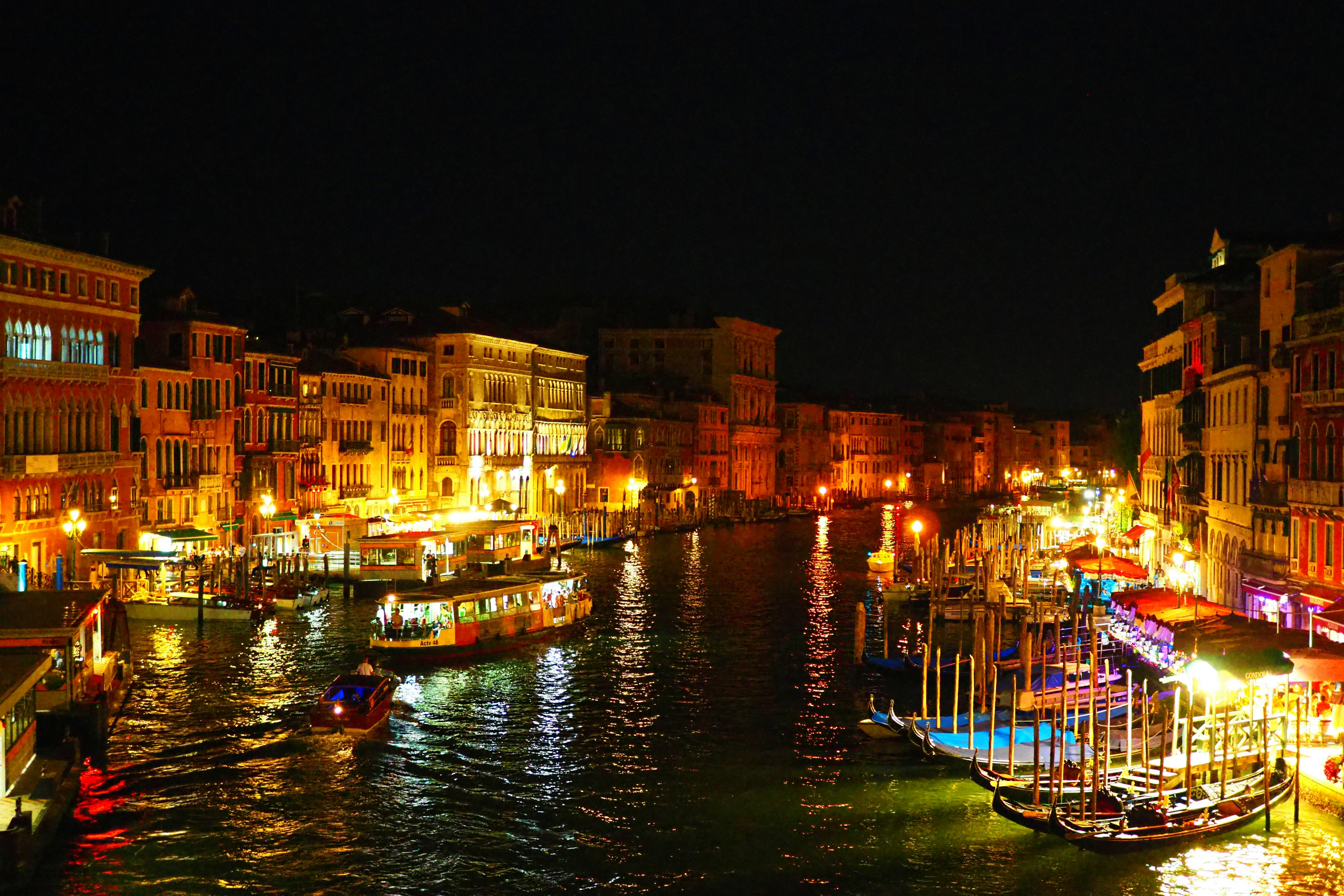 Vista nocturna del canal de Venecia iluminado con luces y góndolas