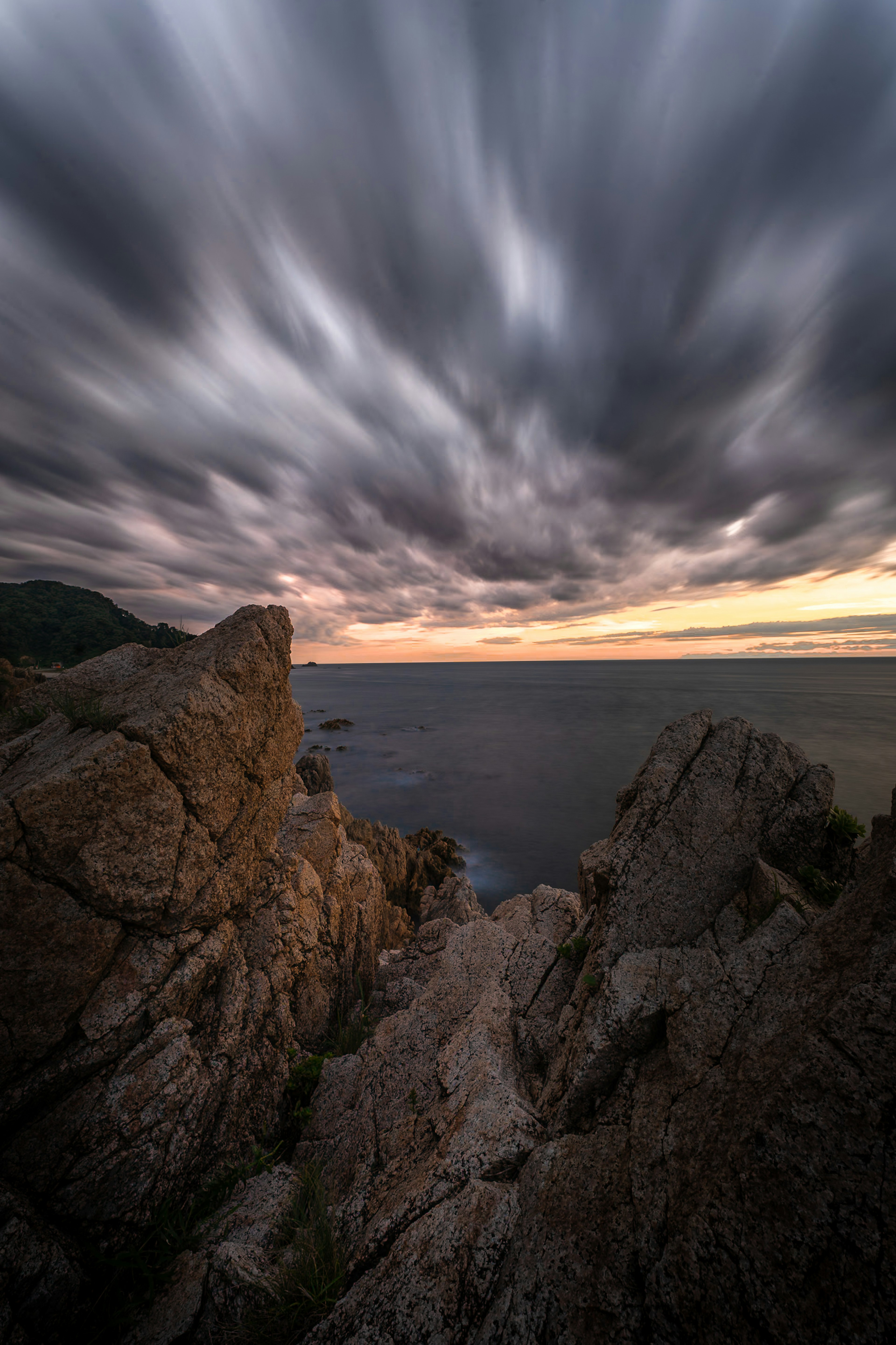 Dramatic seascape with rocky cliffs and dark clouds at sunset