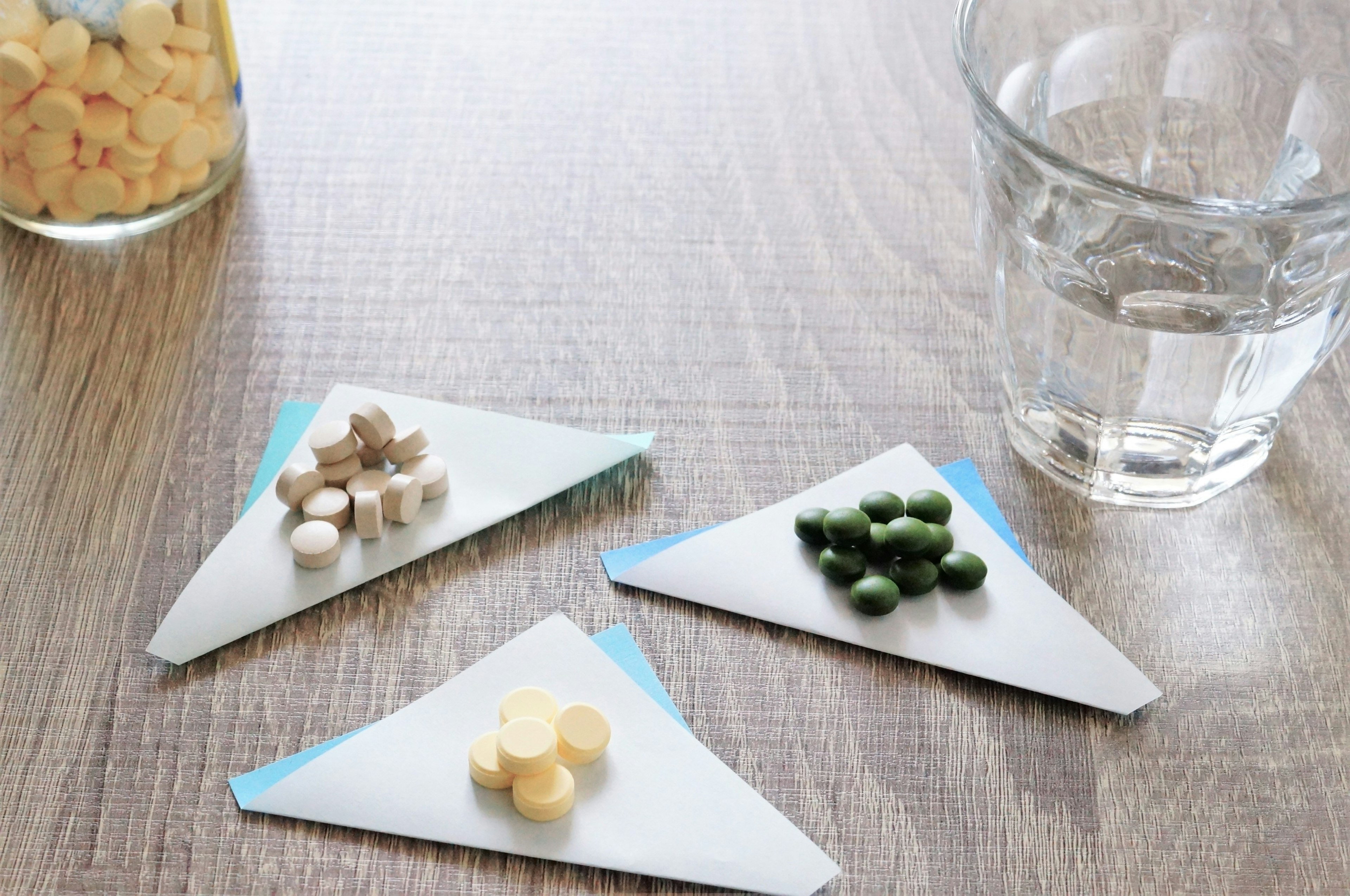 Supplements arranged on triangular paper with a glass of water