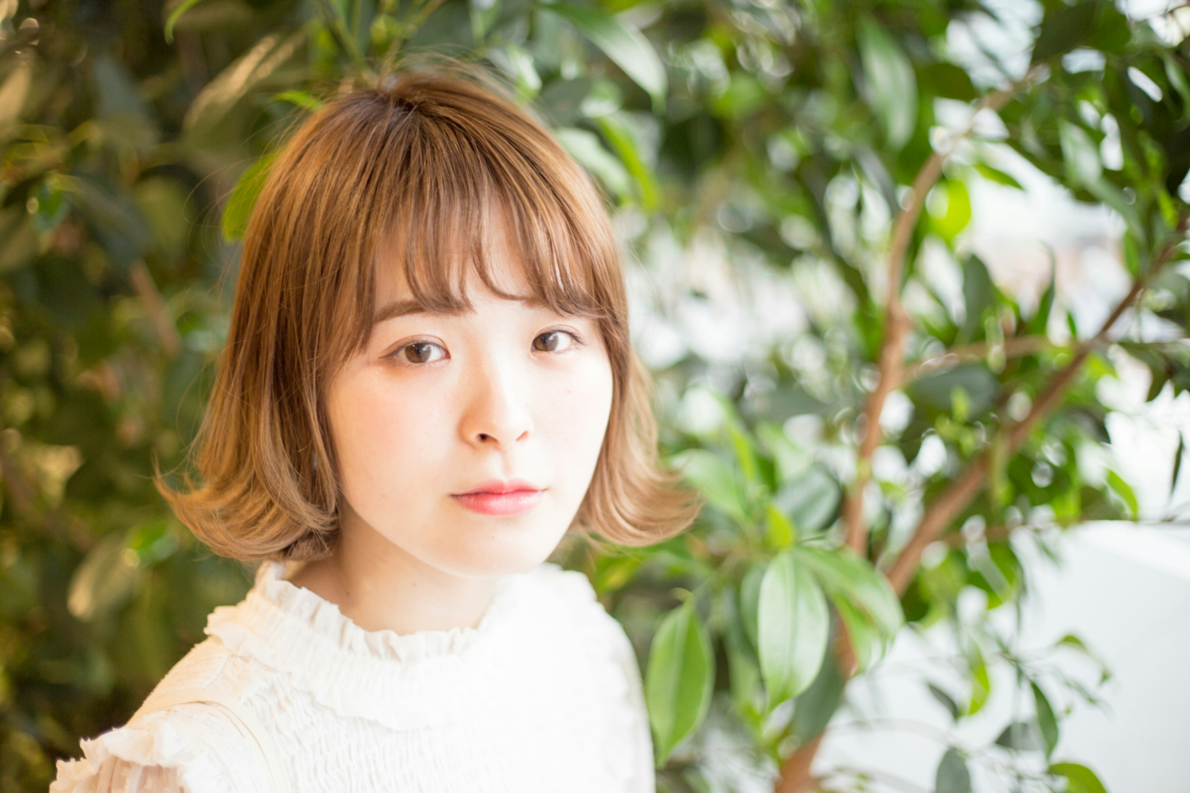 Retrato de una mujer frente a plantas verdes Fondo brillante y expresión suave