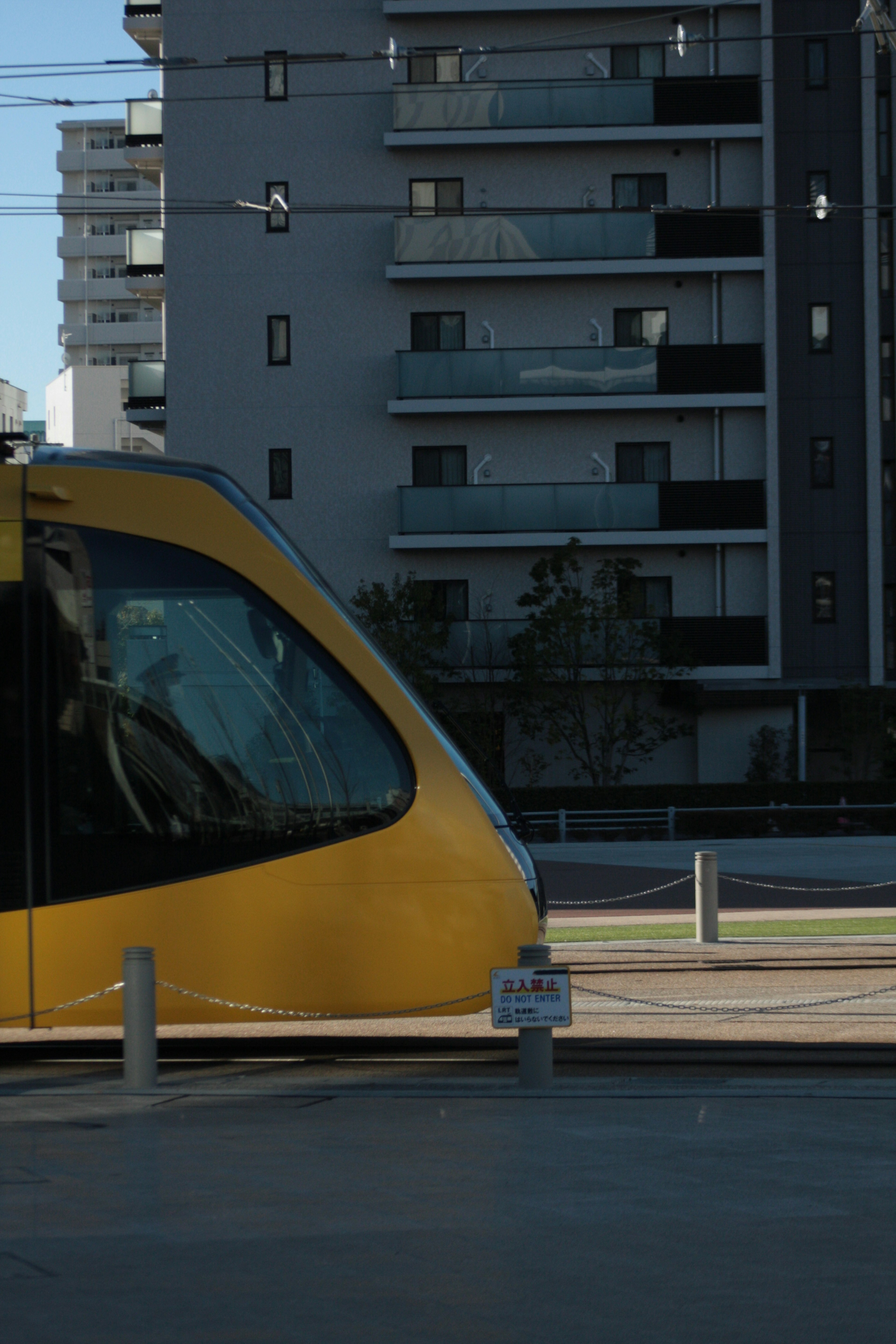 A yellow tram in the foreground with modern apartment buildings in the background