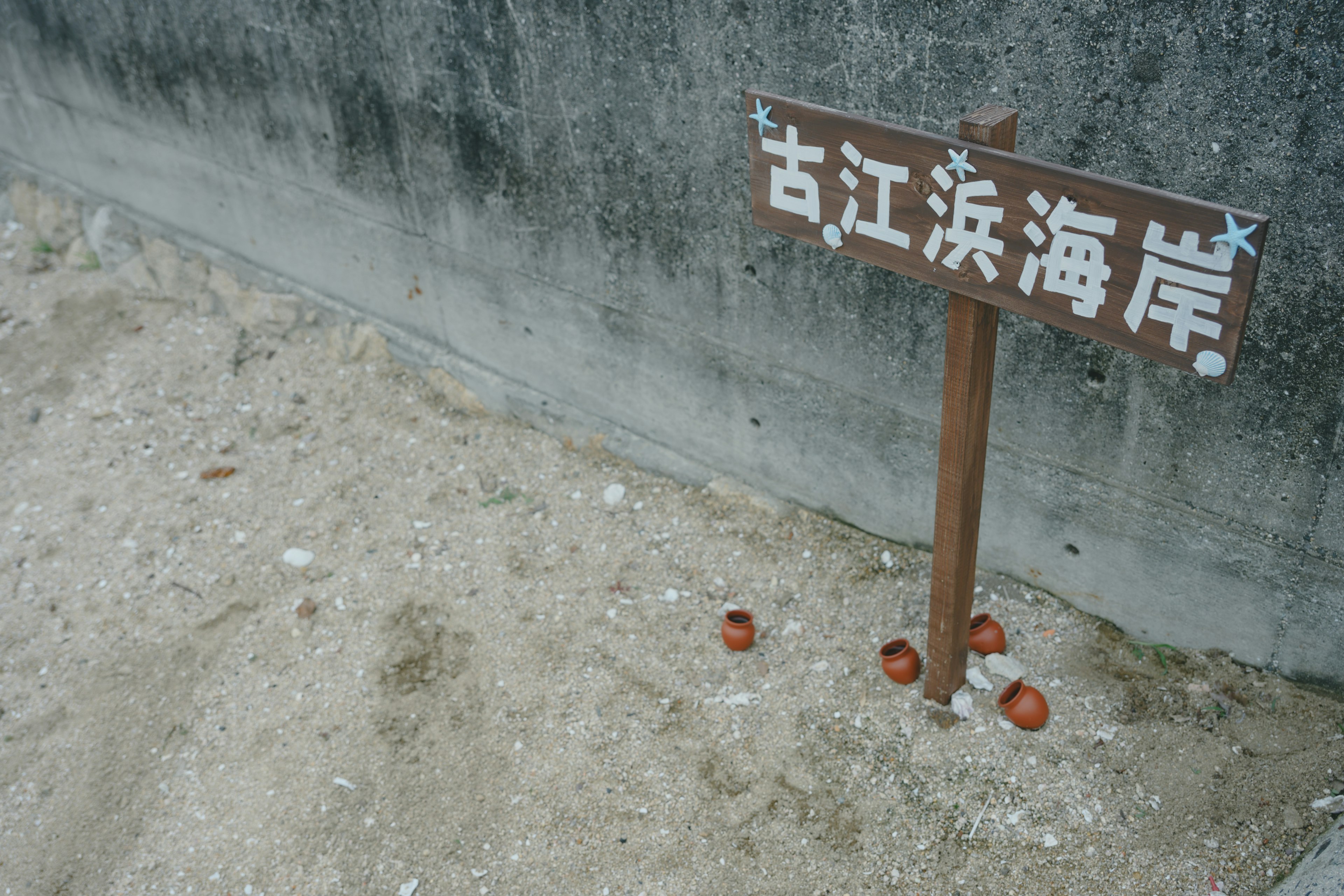 A sign indicating the Goei Beach with a sandy area and scattered pots