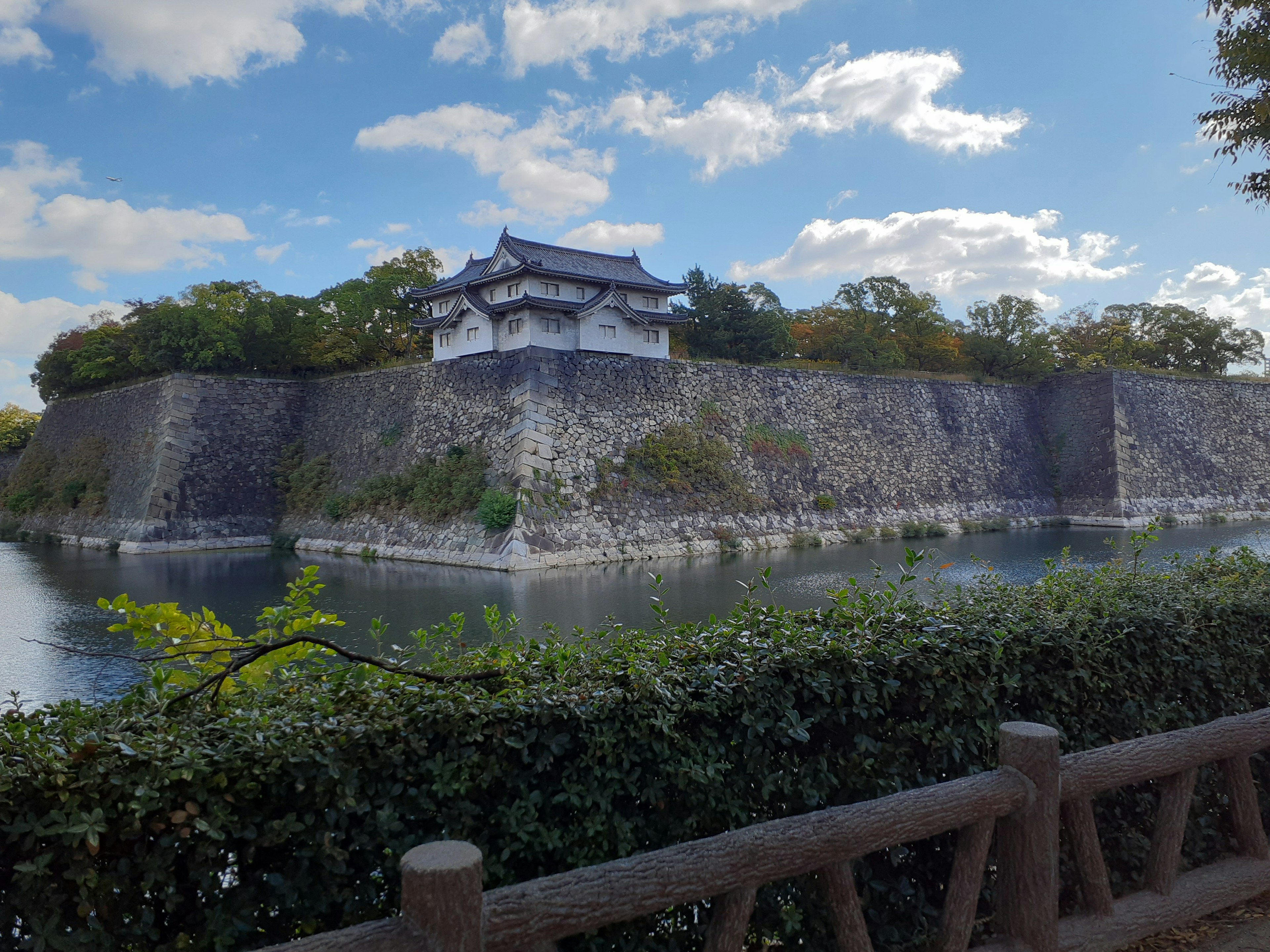 Vue d'un château japonais avec de beaux murs en pierre se reflétant dans l'eau sous un ciel bleu