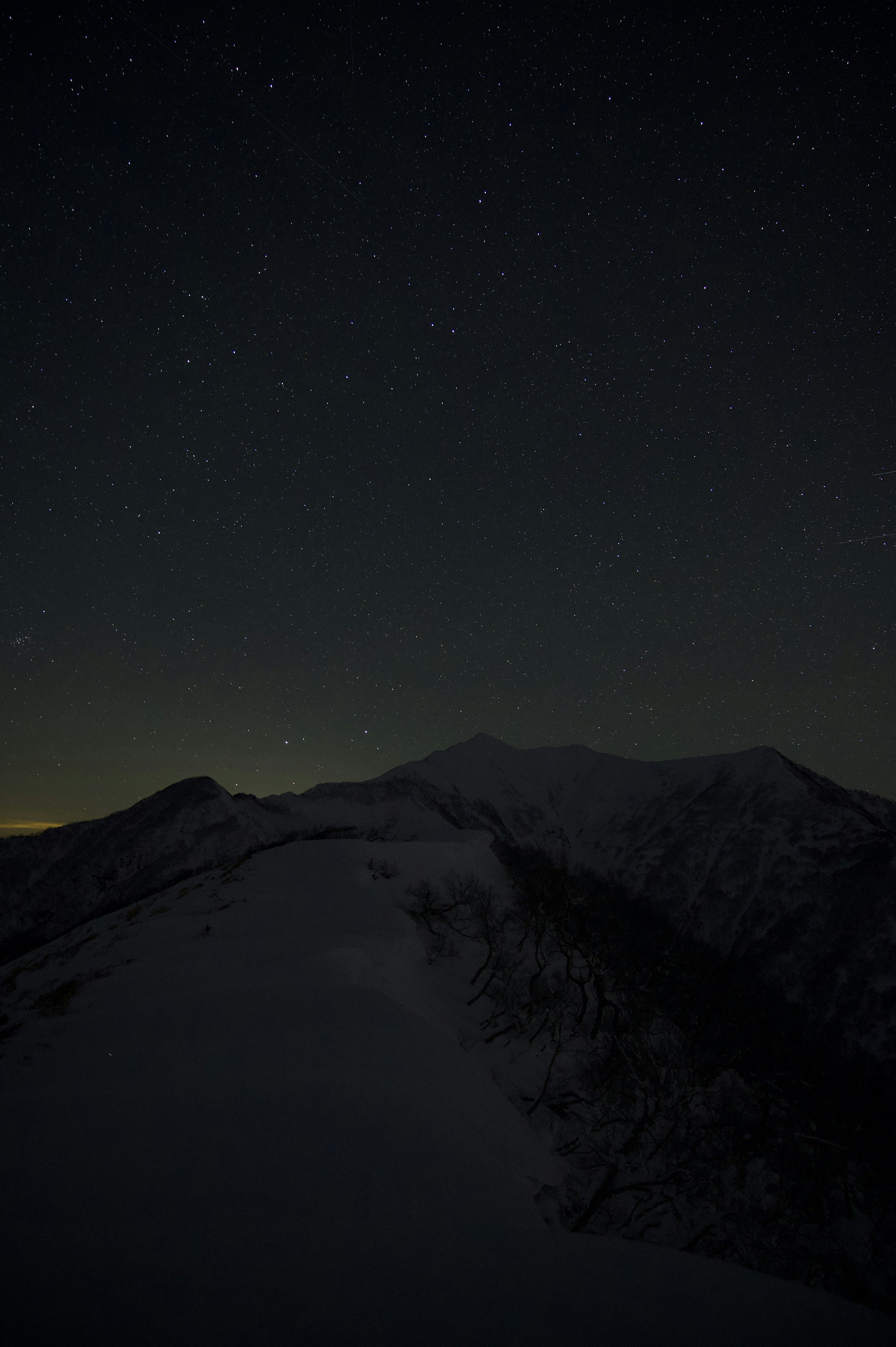 Langit malam berbintang dengan siluet gunung bersalju