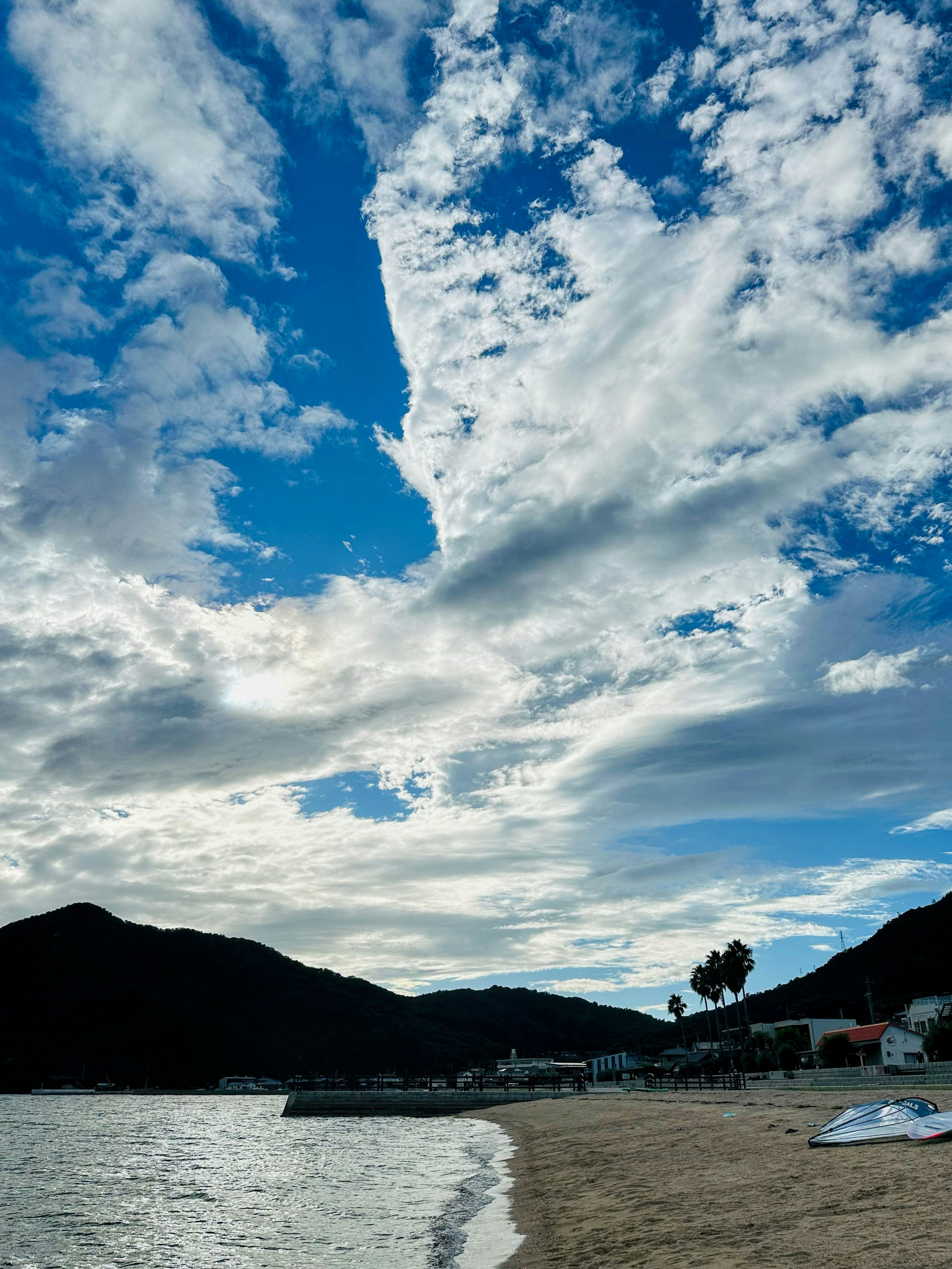 Malersiche Strandansicht mit blauem Himmel und weißen Wolken Berge und Wasser