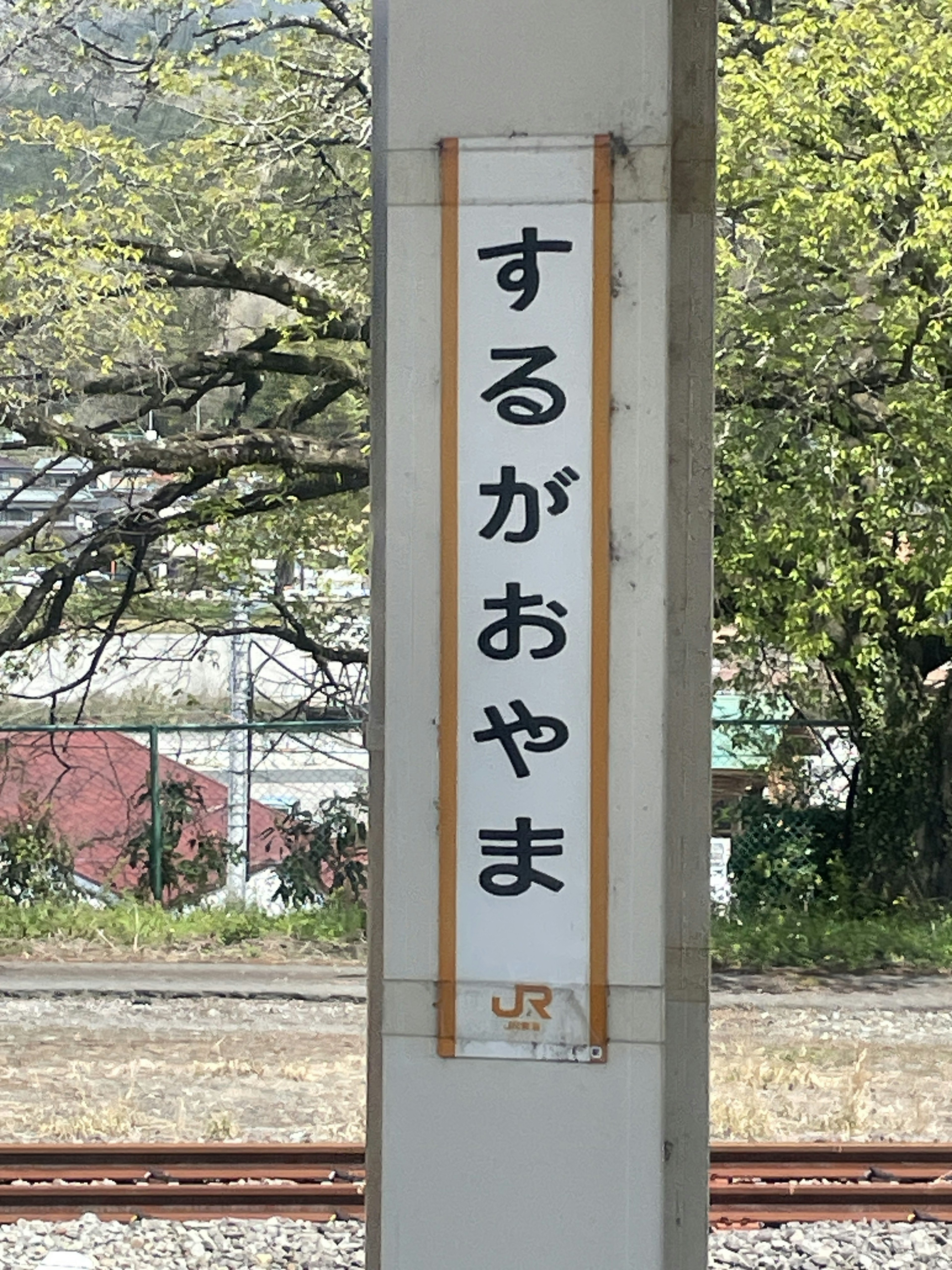 Papan stasiun Surugaoyama dengan vegetasi di sekitarnya