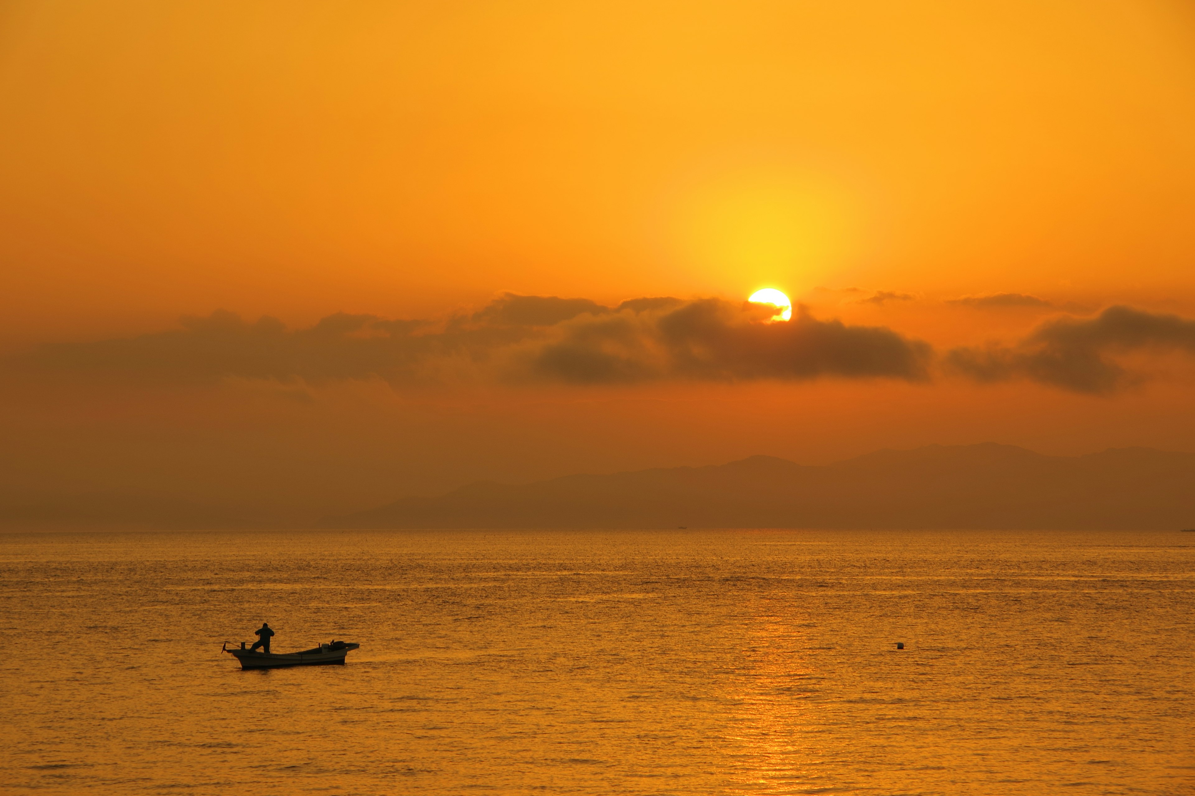 一艘船在海上轻轻漂浮，橙色日落渐渐西沉