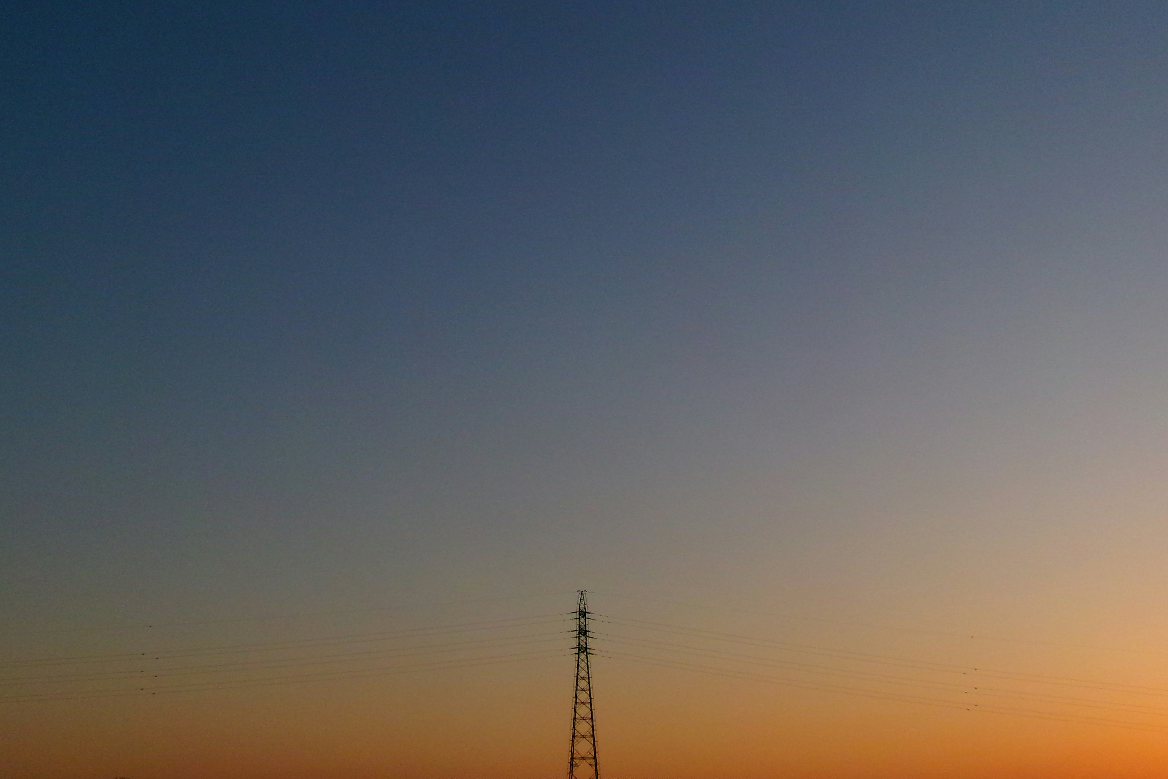 Silhouette di una torre di comunicazione contro un cielo al tramonto