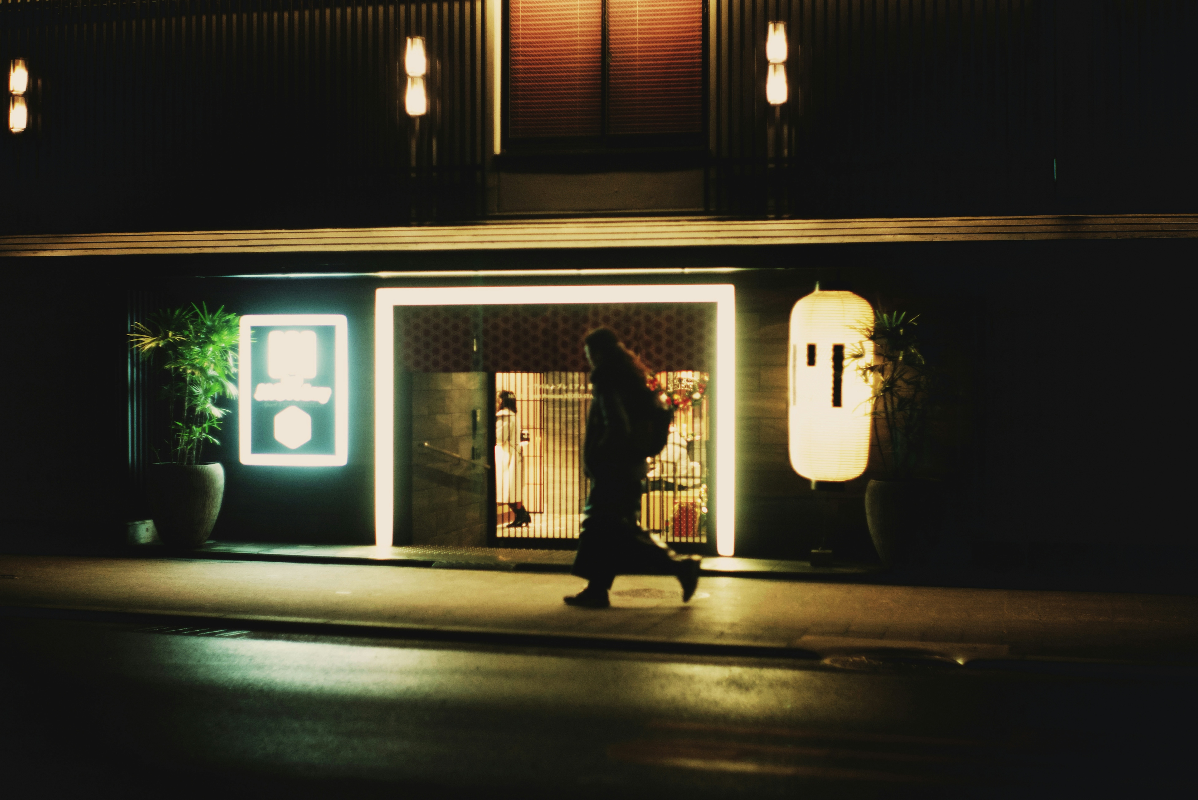 夜の街を歩く人と明かりに照らされた店舗の外観