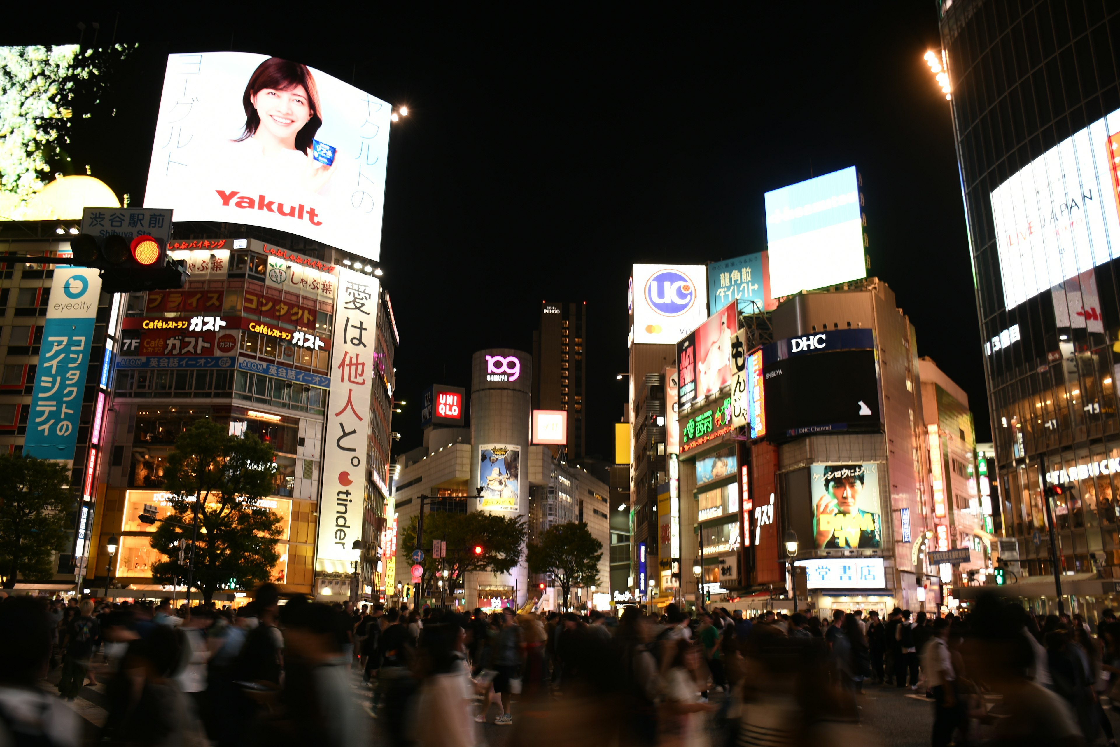 Cruce de Shibuya de noche con anuncios brillantes y multitudes