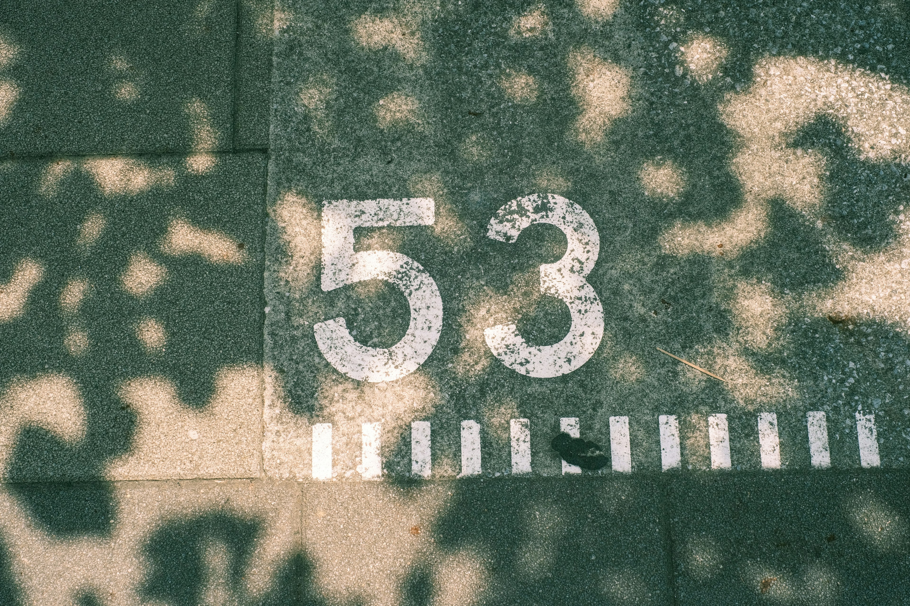 Number 53 on a pavement with shadows